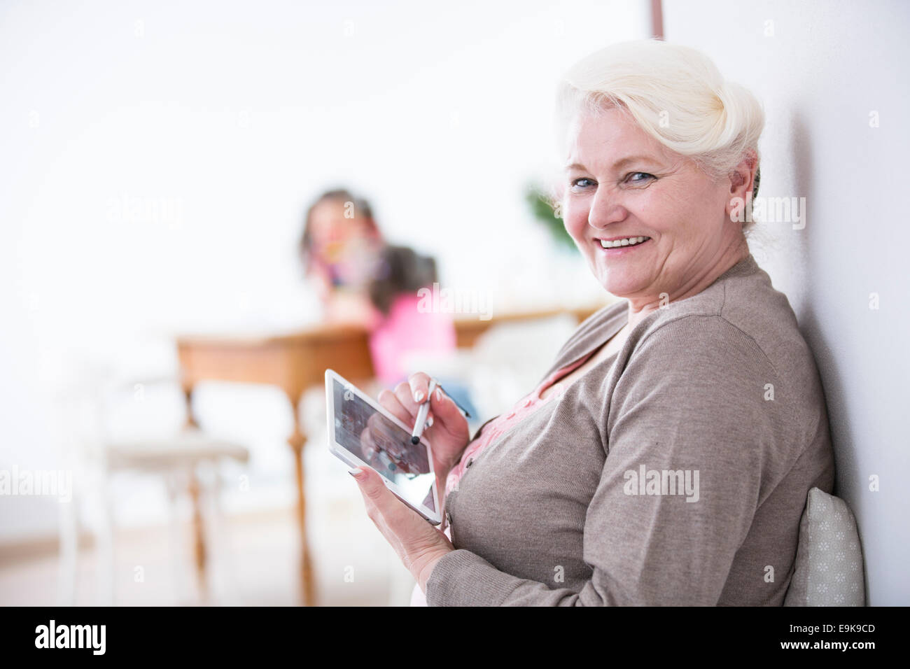 Portrait of happy senior woman using digital tablet with stylus at home Stock Photo