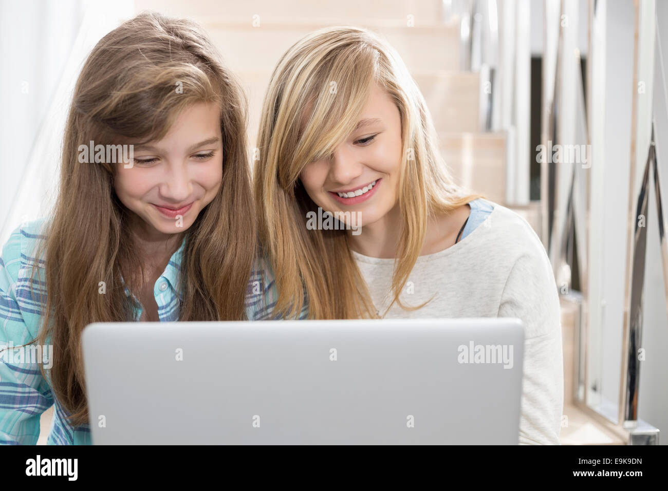 Sisters using laptop on stairway Stock Photo