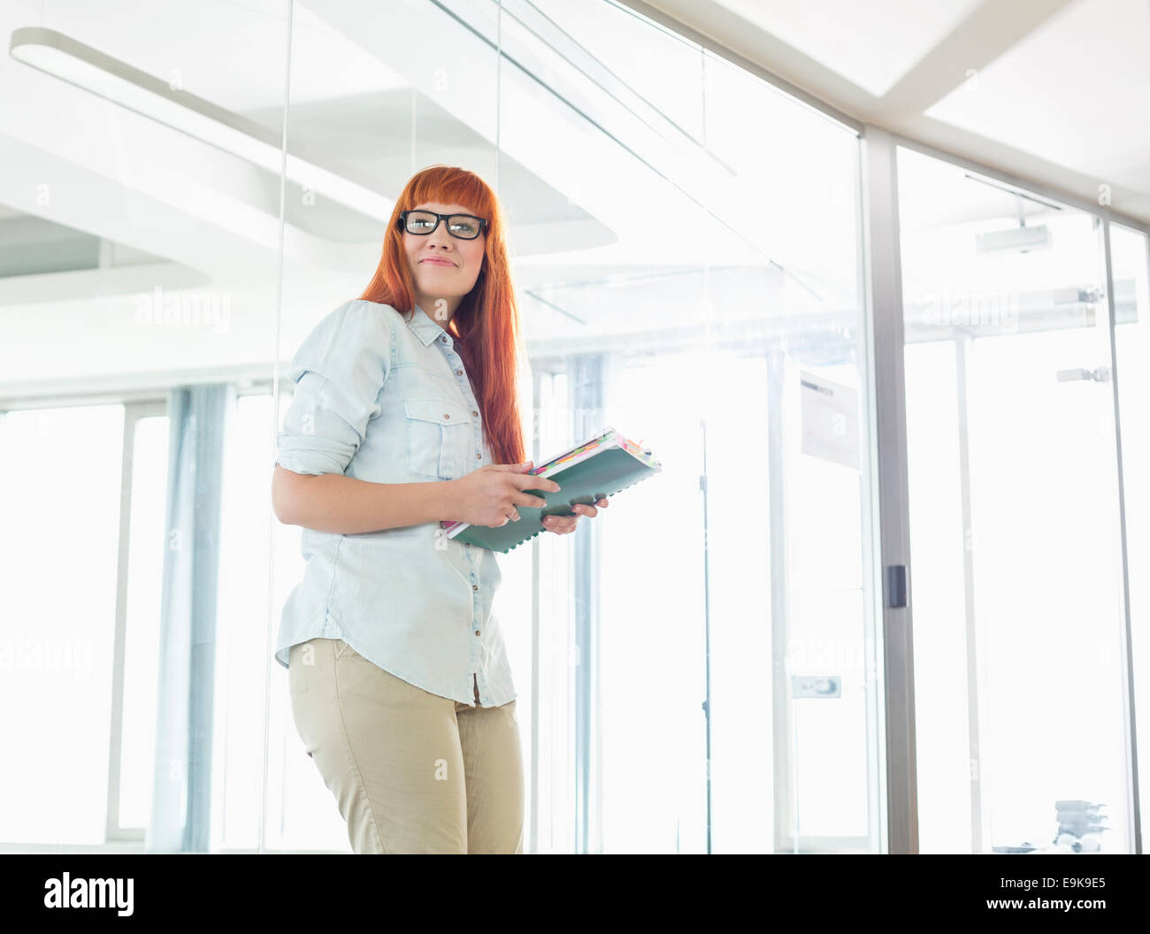 Creative businesswoman looking away while holding files in office Stock Photo
