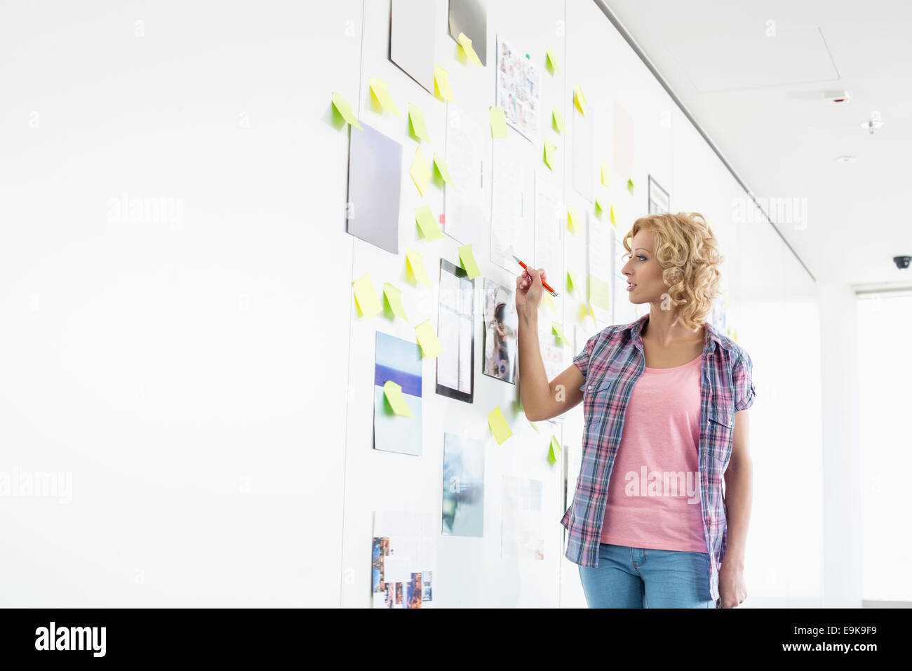 Creative businesswoman writing on sticky paper in office Stock Photo ...