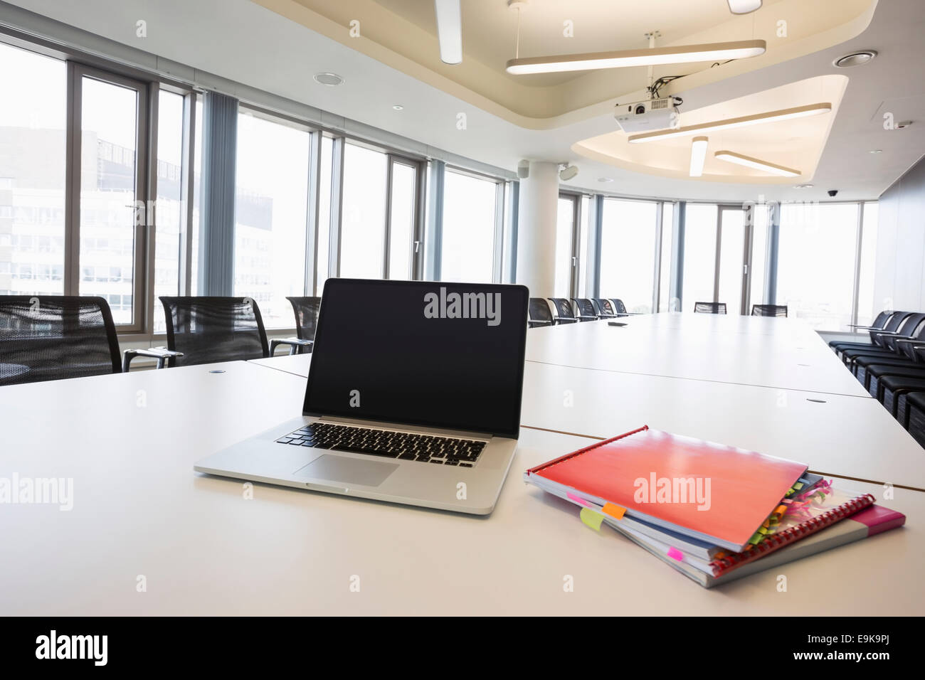 Laptop and files on empty conference table in creative office Stock Photo