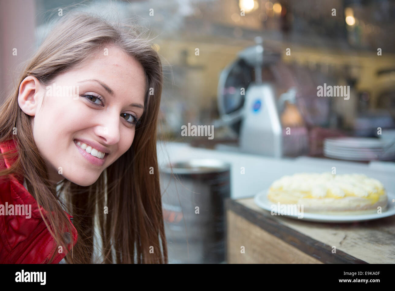 Portrait of happy woman by display cabinet in cafe Stock Photo
