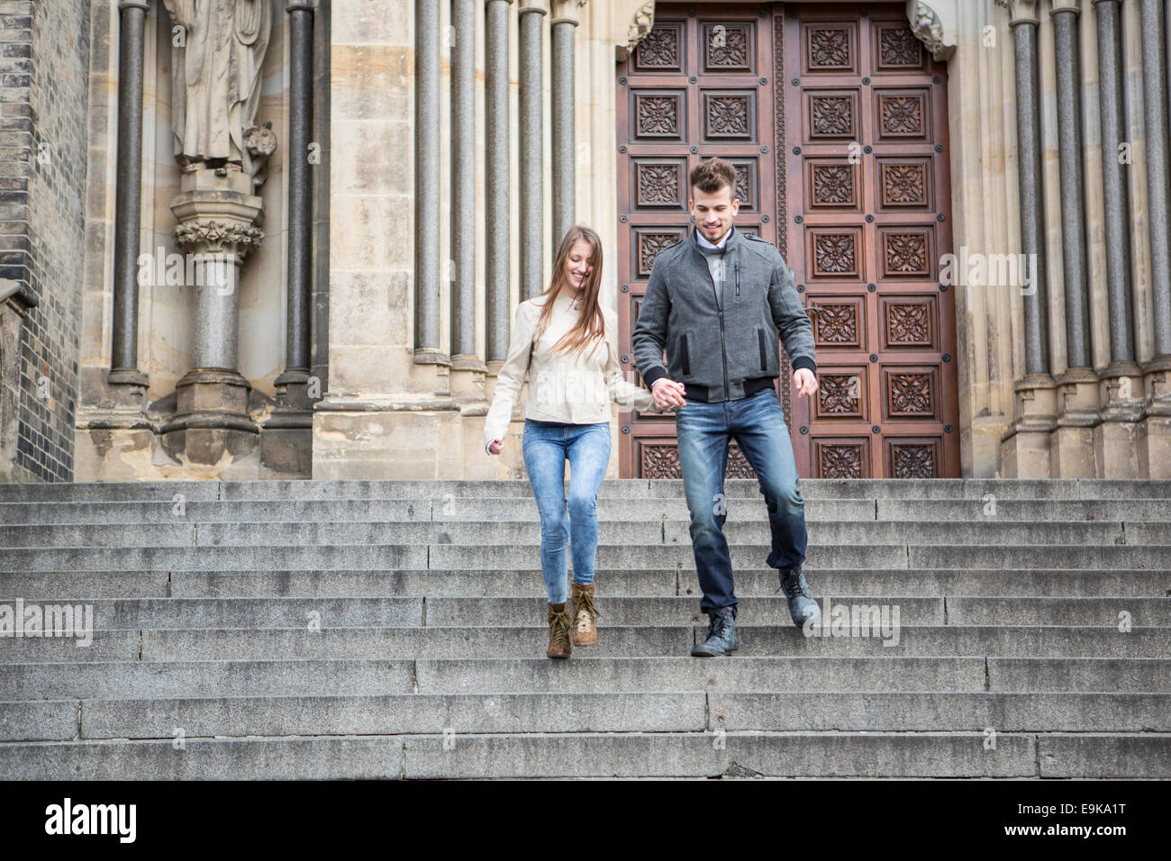 Full length of young couple moving down steps against building Stock Photo