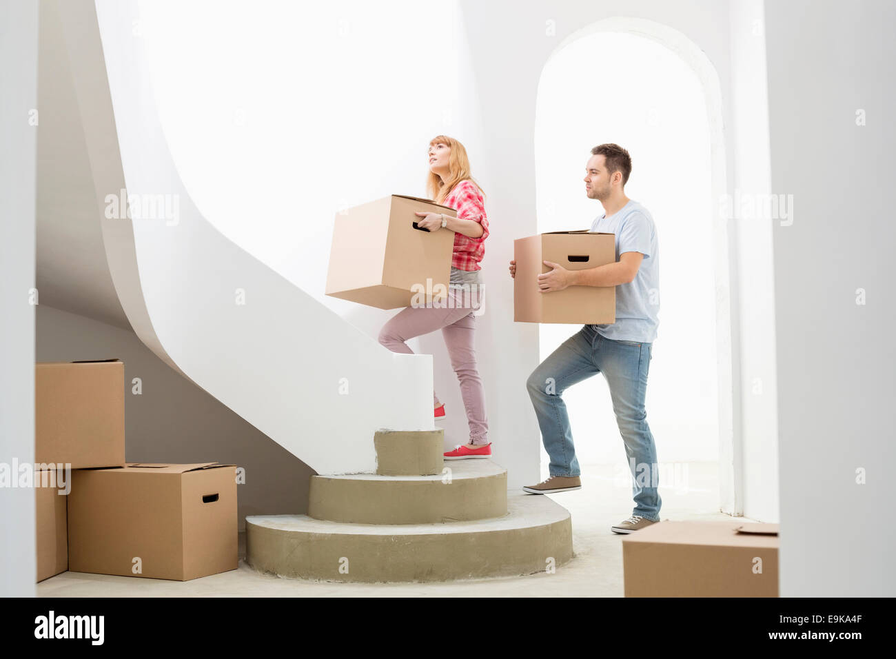 Couple carrying cardboard boxes up stairs in new house Stock Photo