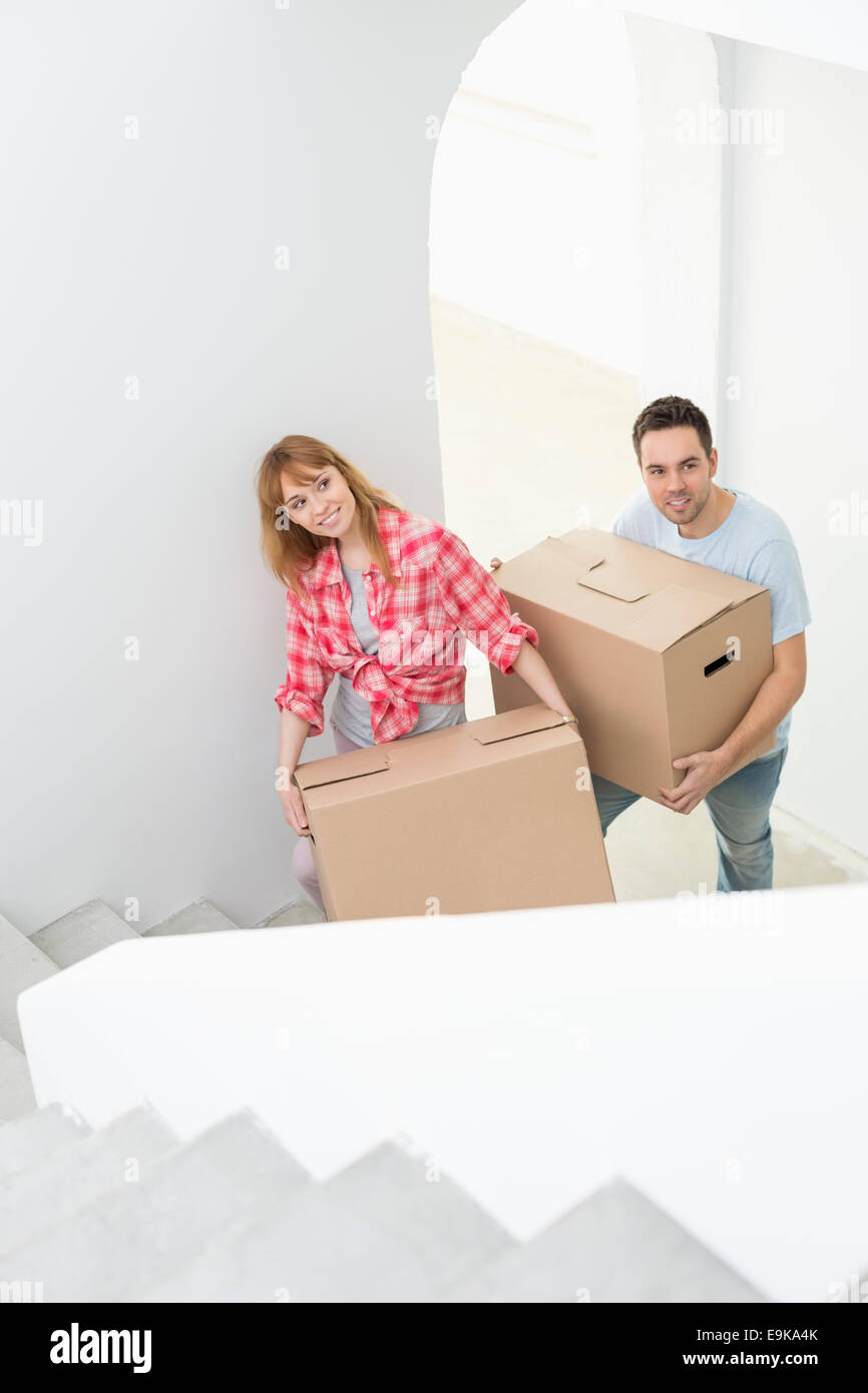 Couple carrying moving boxes up stairs in new house Stock Photo - Alamy