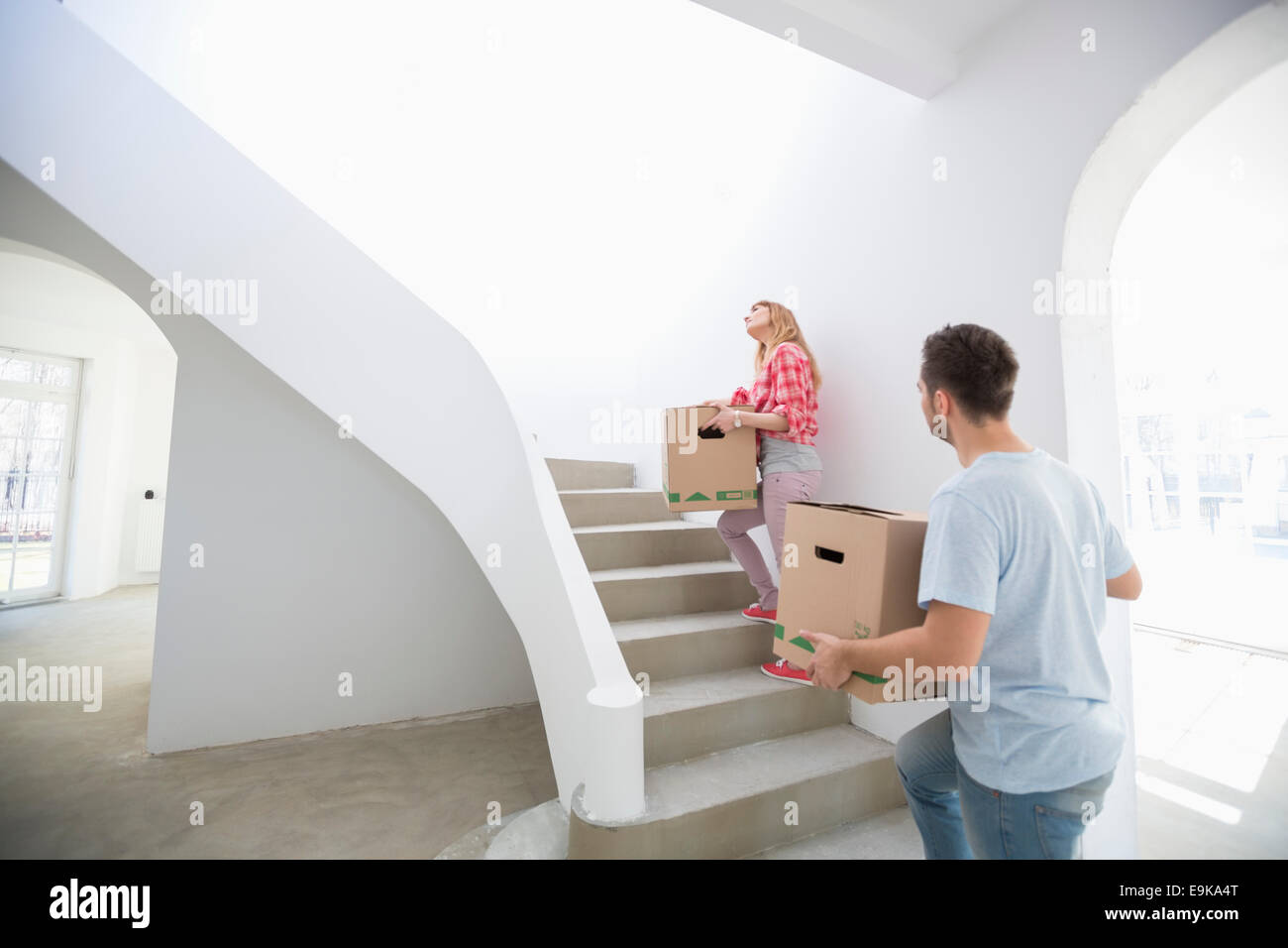 Couple carrying moving boxes up stairs in new house Stock Photo