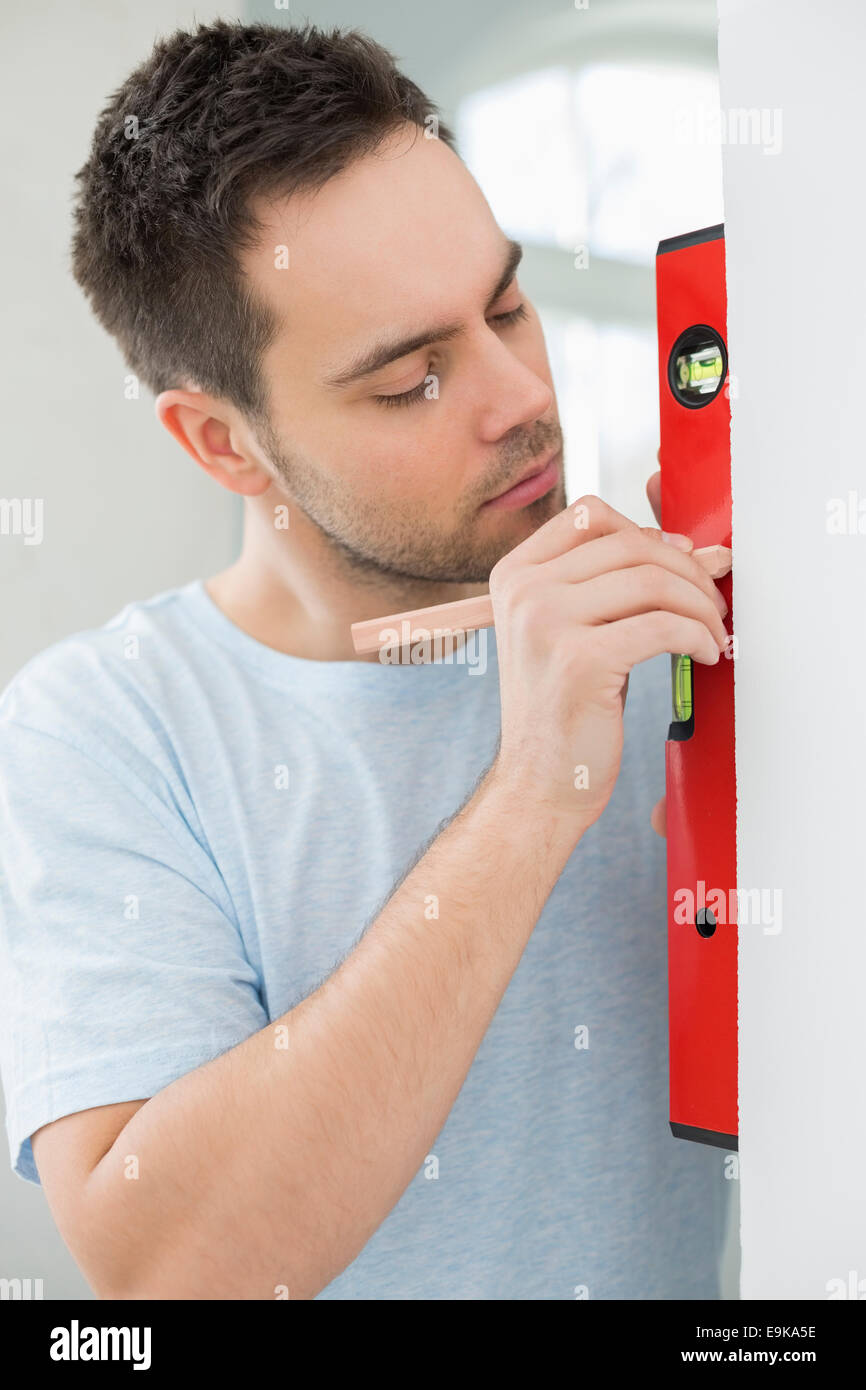 Mid-adult man marking on wall with level Stock Photo