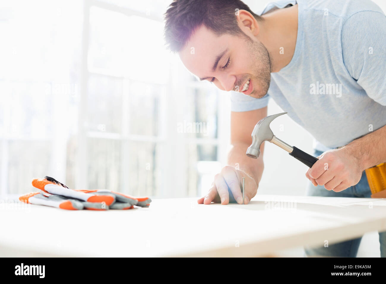 Mid-adult man nailing in table Stock Photo