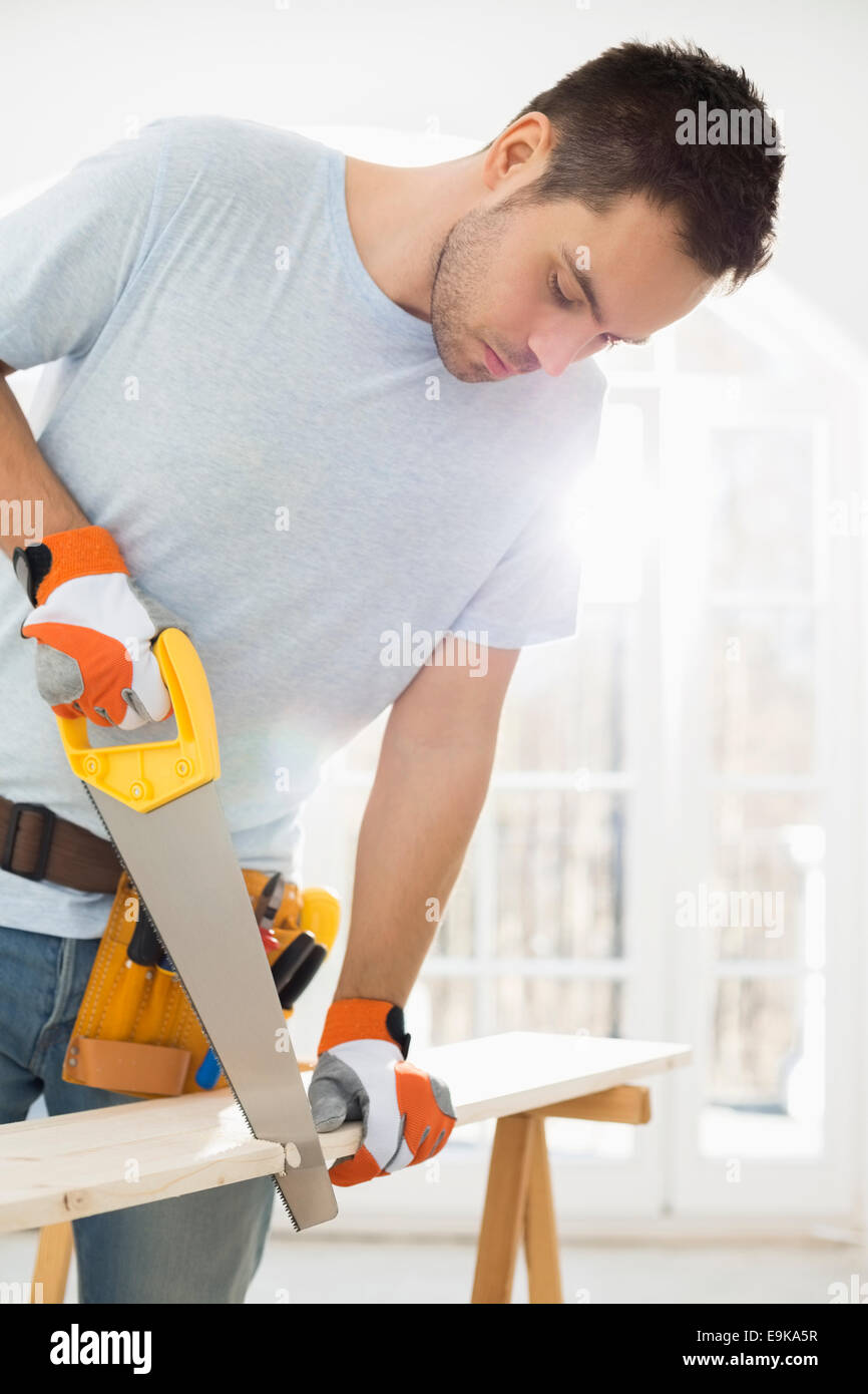 Man sawing wood in new house Stock Photo