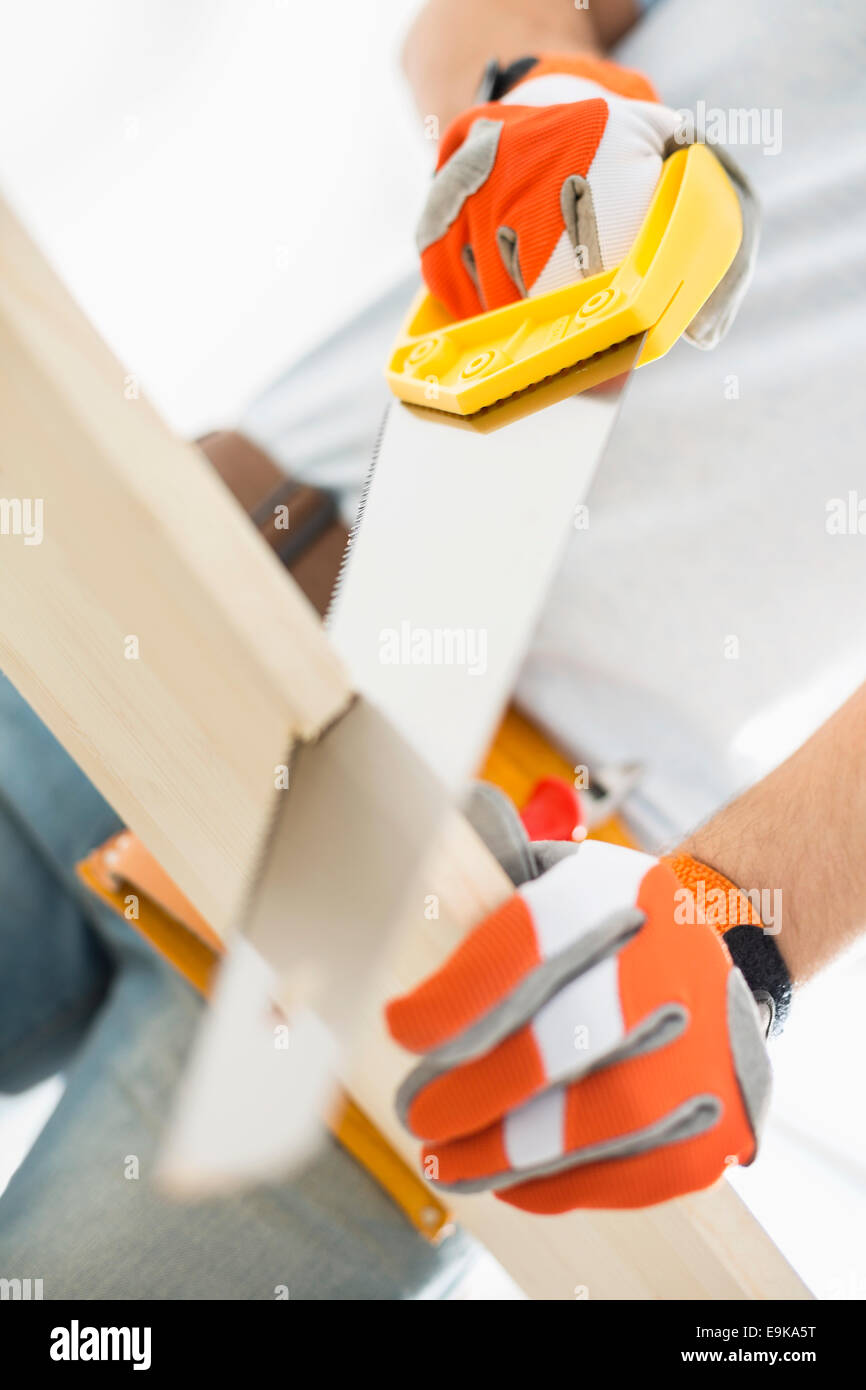 Midsection of man sawing plank Stock Photo