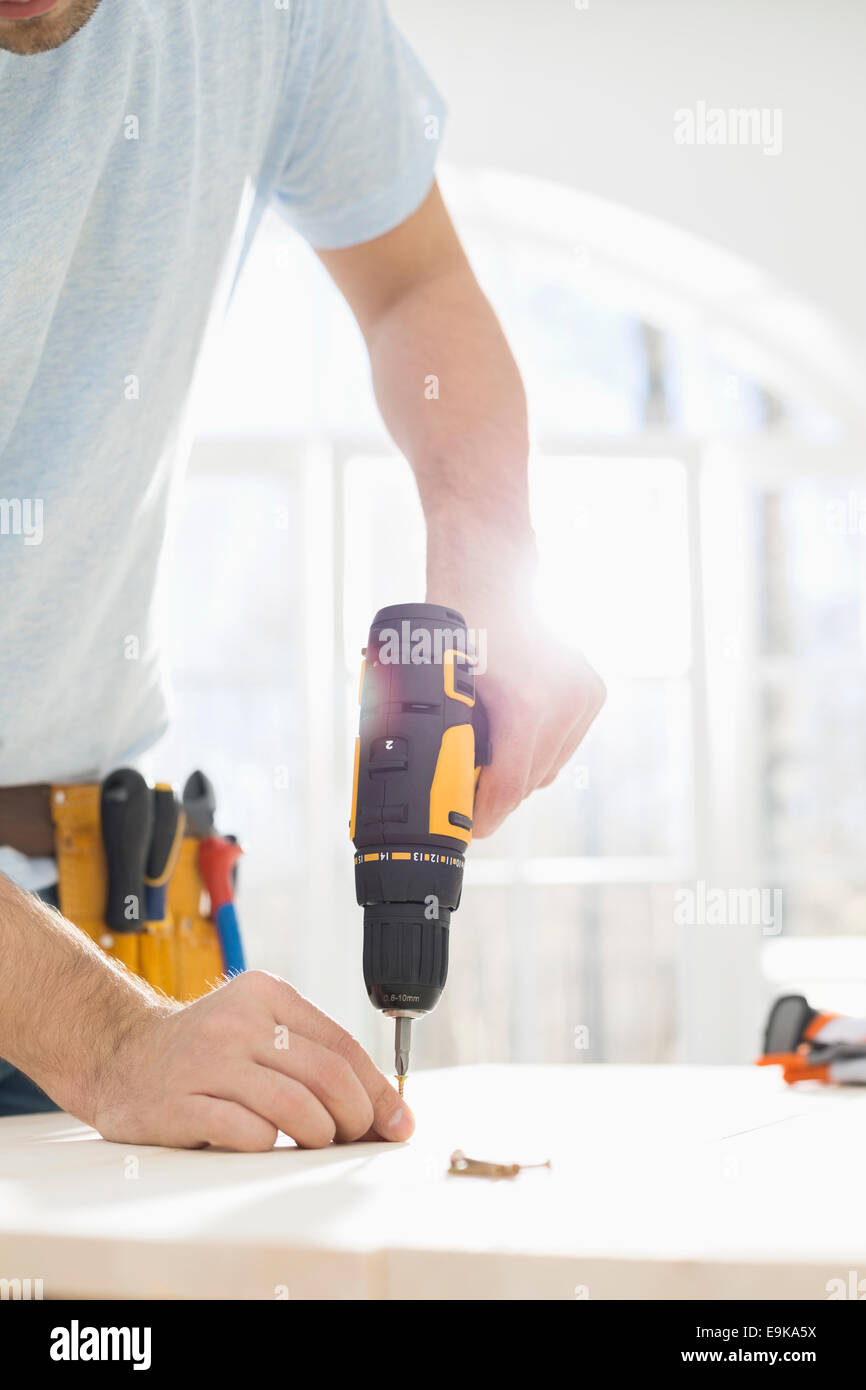 Midsection of man drilling nail on table Stock Photo