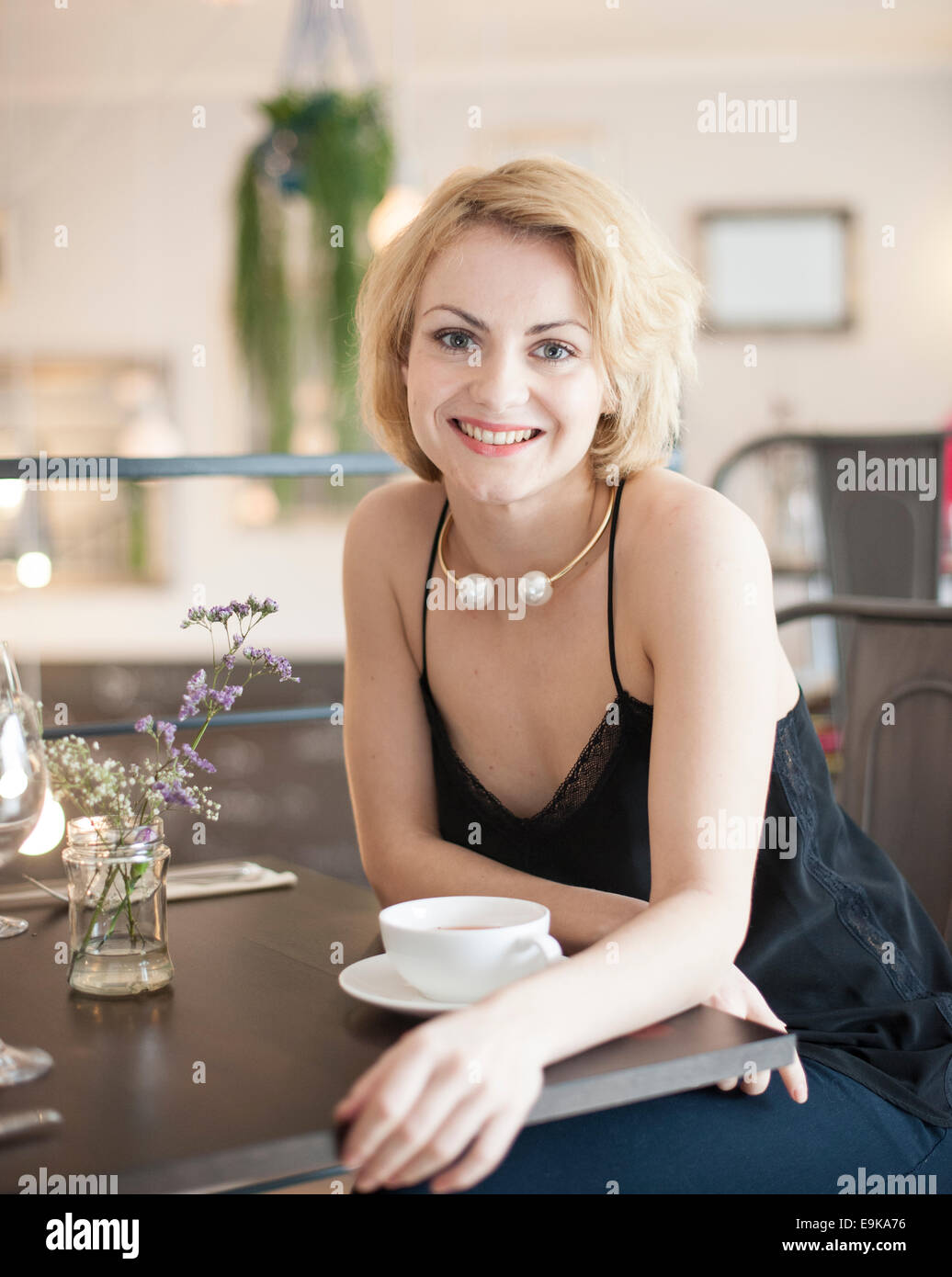Portrait of happy young woman sitting at restaurant table Stock Photo