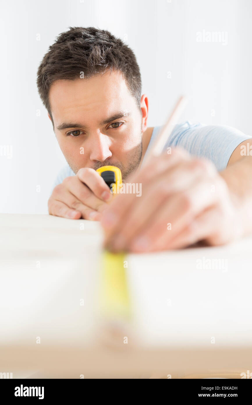 Mid-adult man marking table with measure tape Stock Photo