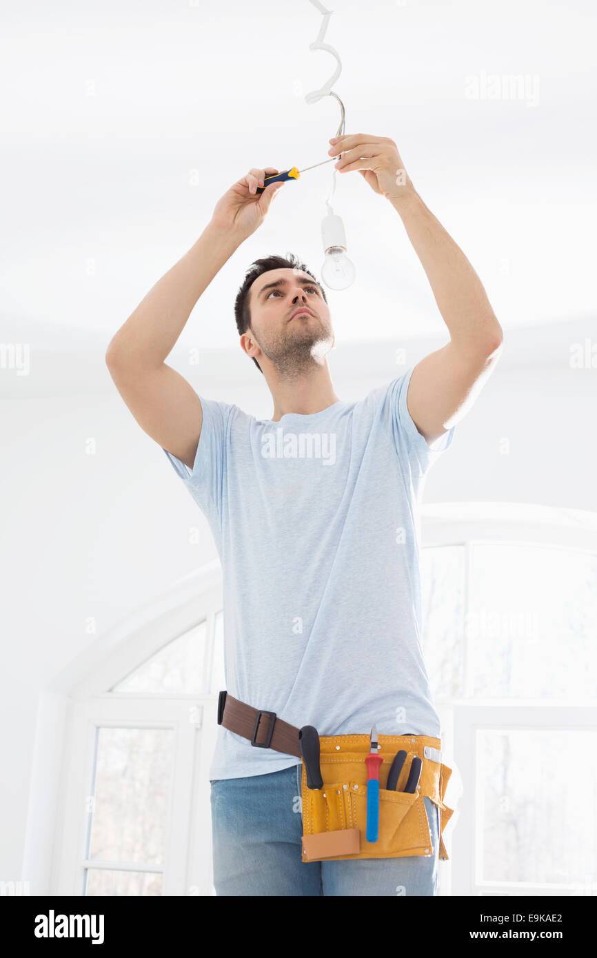 Mid-adult man fixing light bulb wiring in new house Stock Photo - Alamy