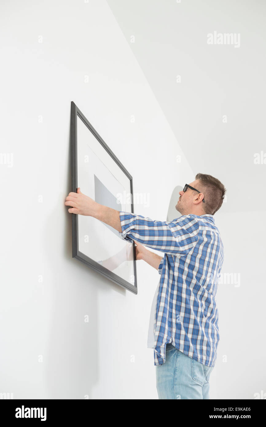 Man positioning picture frame on wall Stock Photo