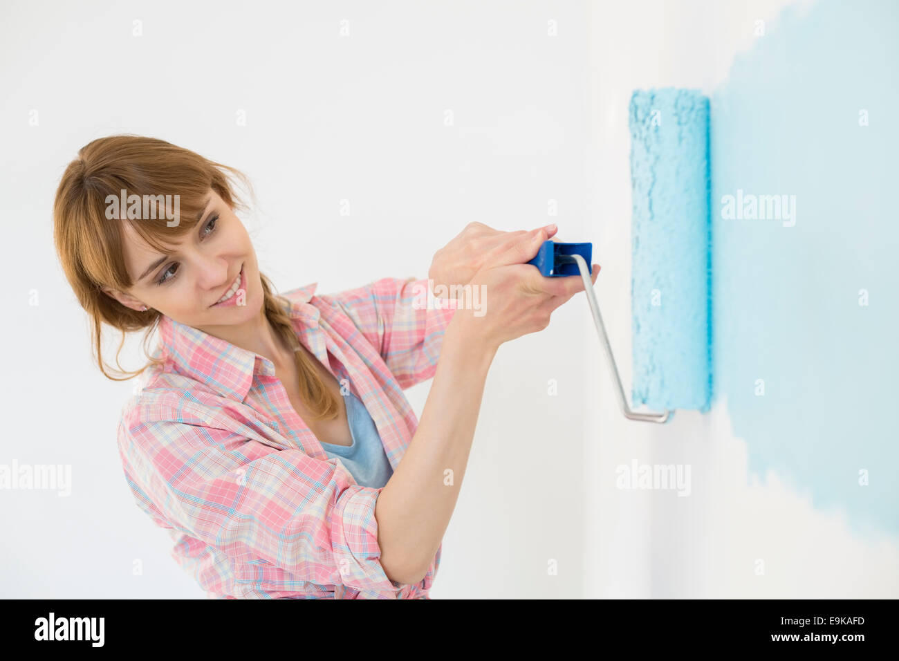 Beautiful woman painting wall with paint roller Stock Photo