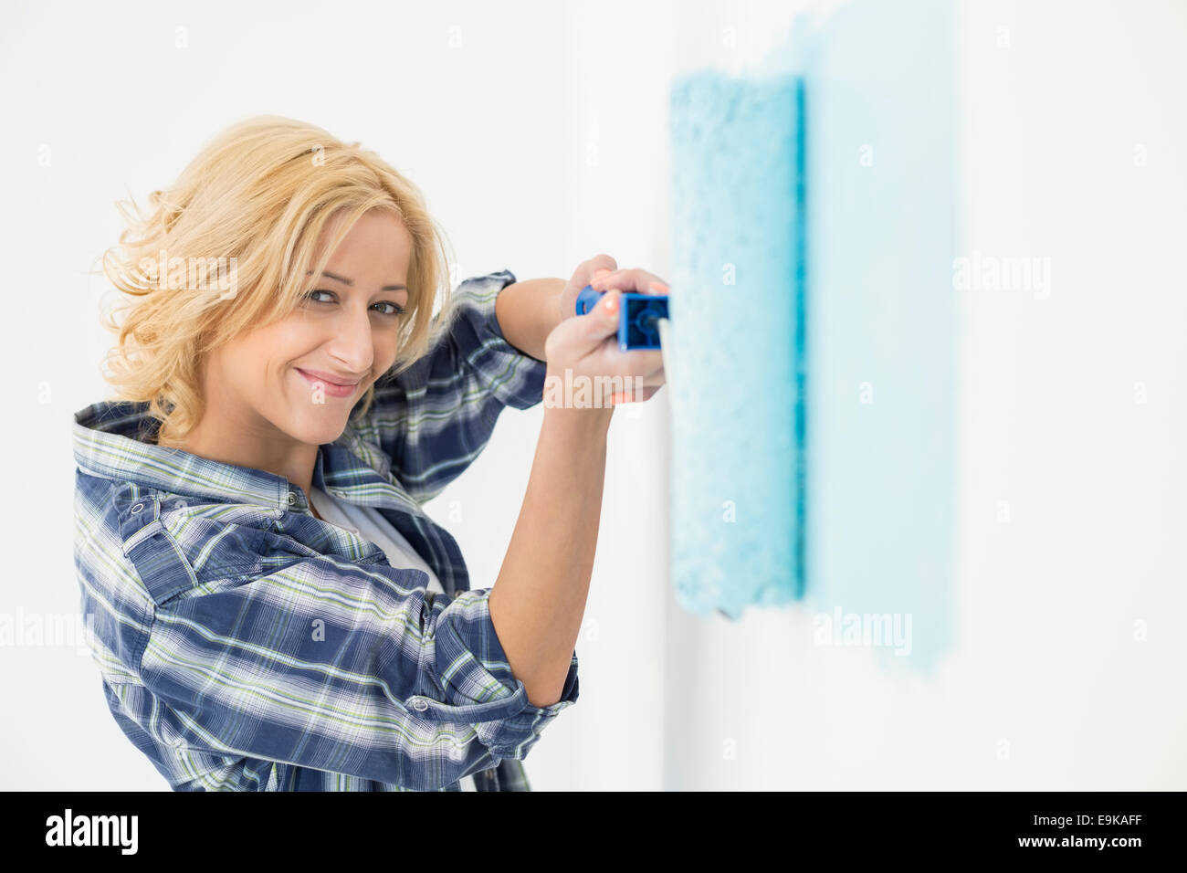 Portrait of beautiful woman painting wall with paint roller Stock Photo ...