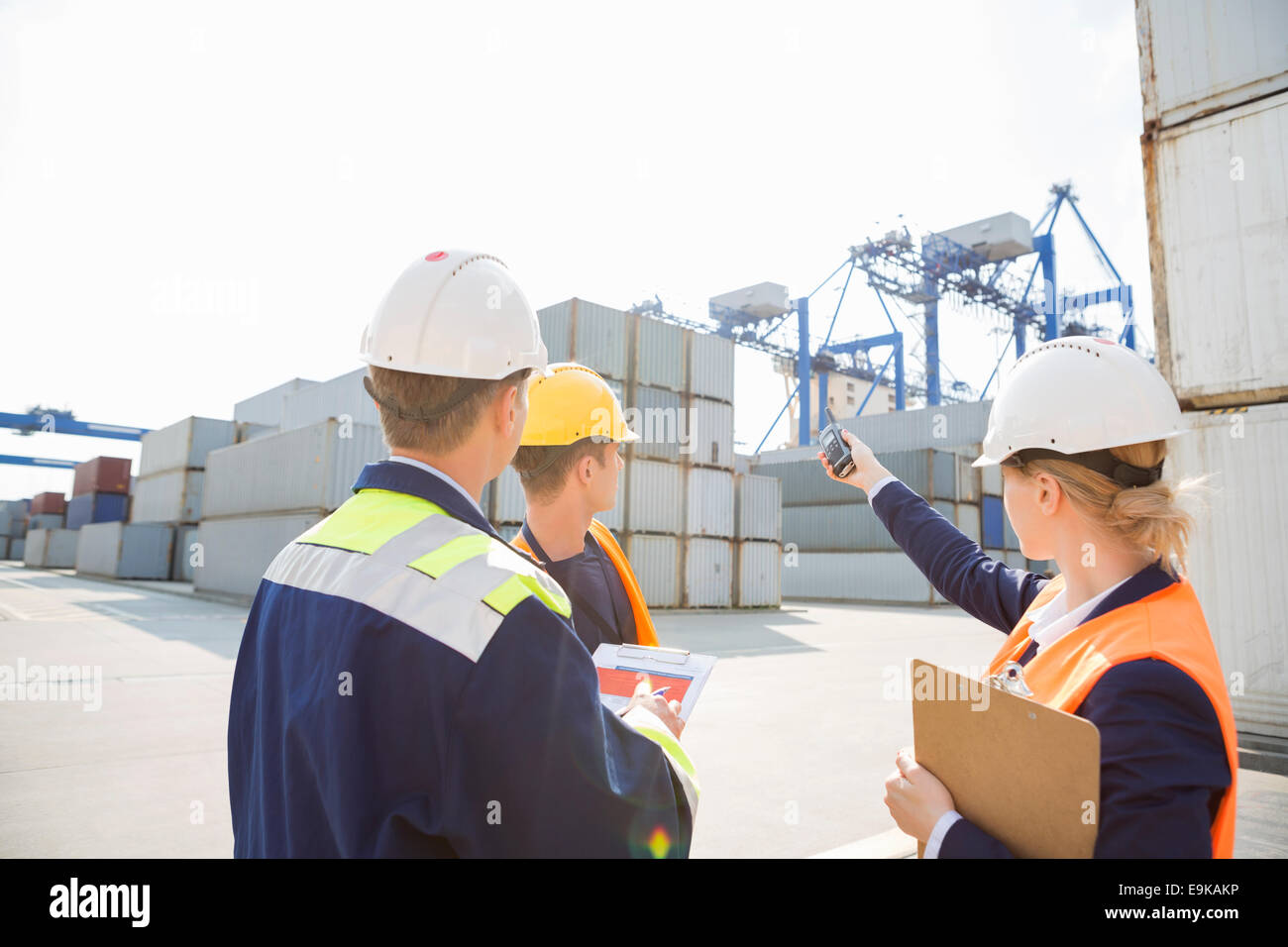 Female supervisor discussing with workers in shipping yard Stock Photo
