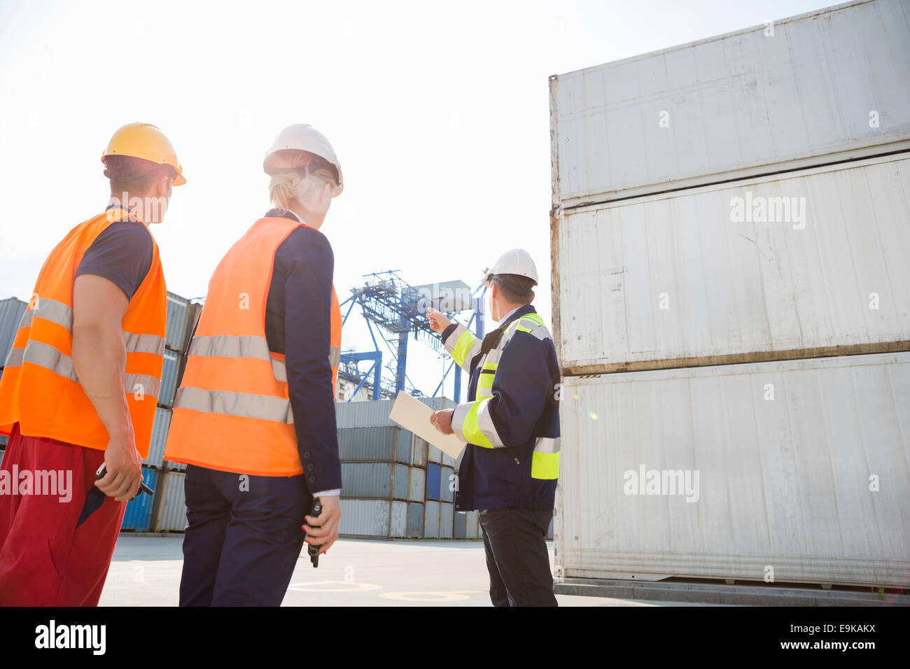 Male supervisor discussing with workers in shipping yard Stock Photo