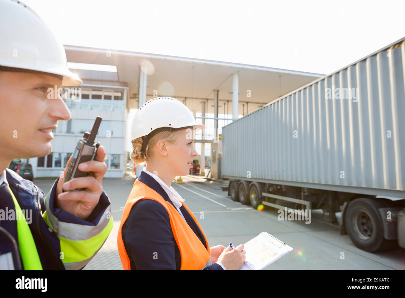 Male and female workers working in shipping yard Stock Photo