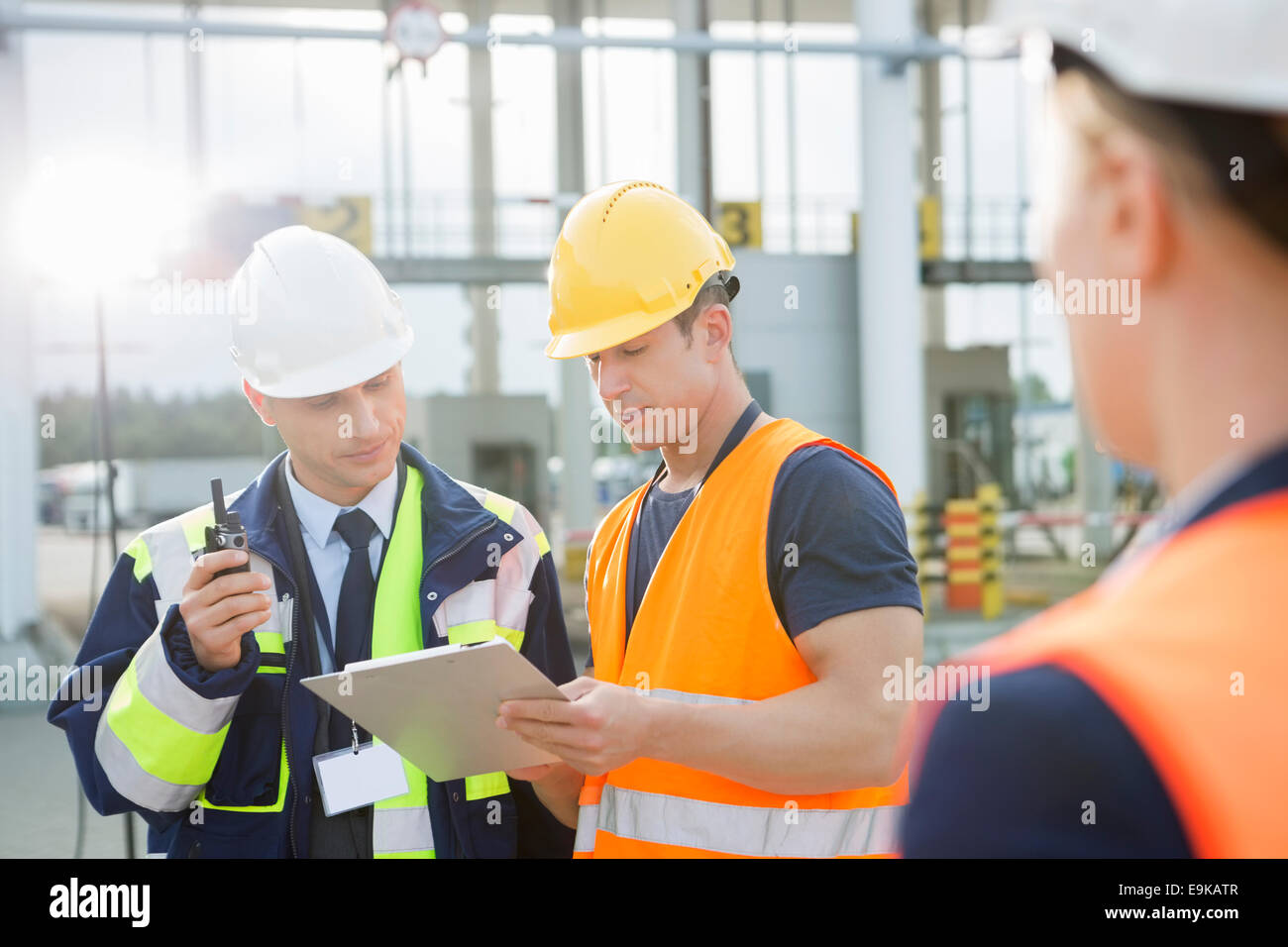 Workers discussing over clipboard in shipping yard Stock Photo