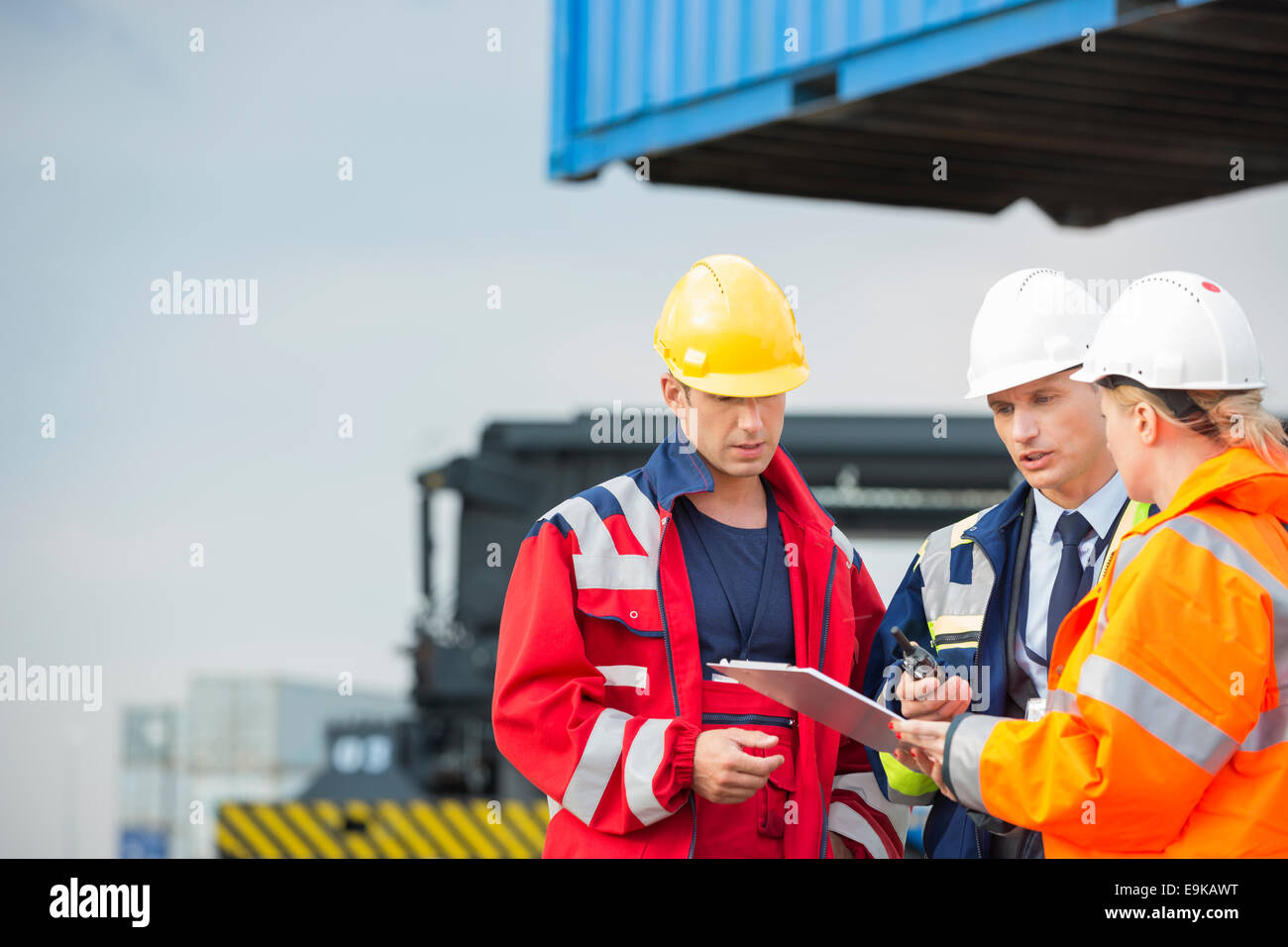Workers discussing over clipboard in shipping yard Stock Photo