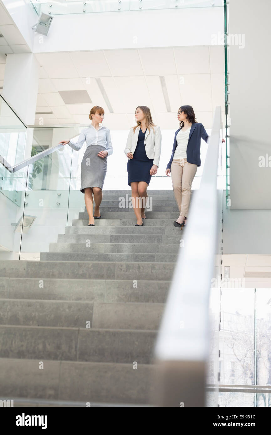 Businesswomen conversing while moving down steps in office Stock Photo
