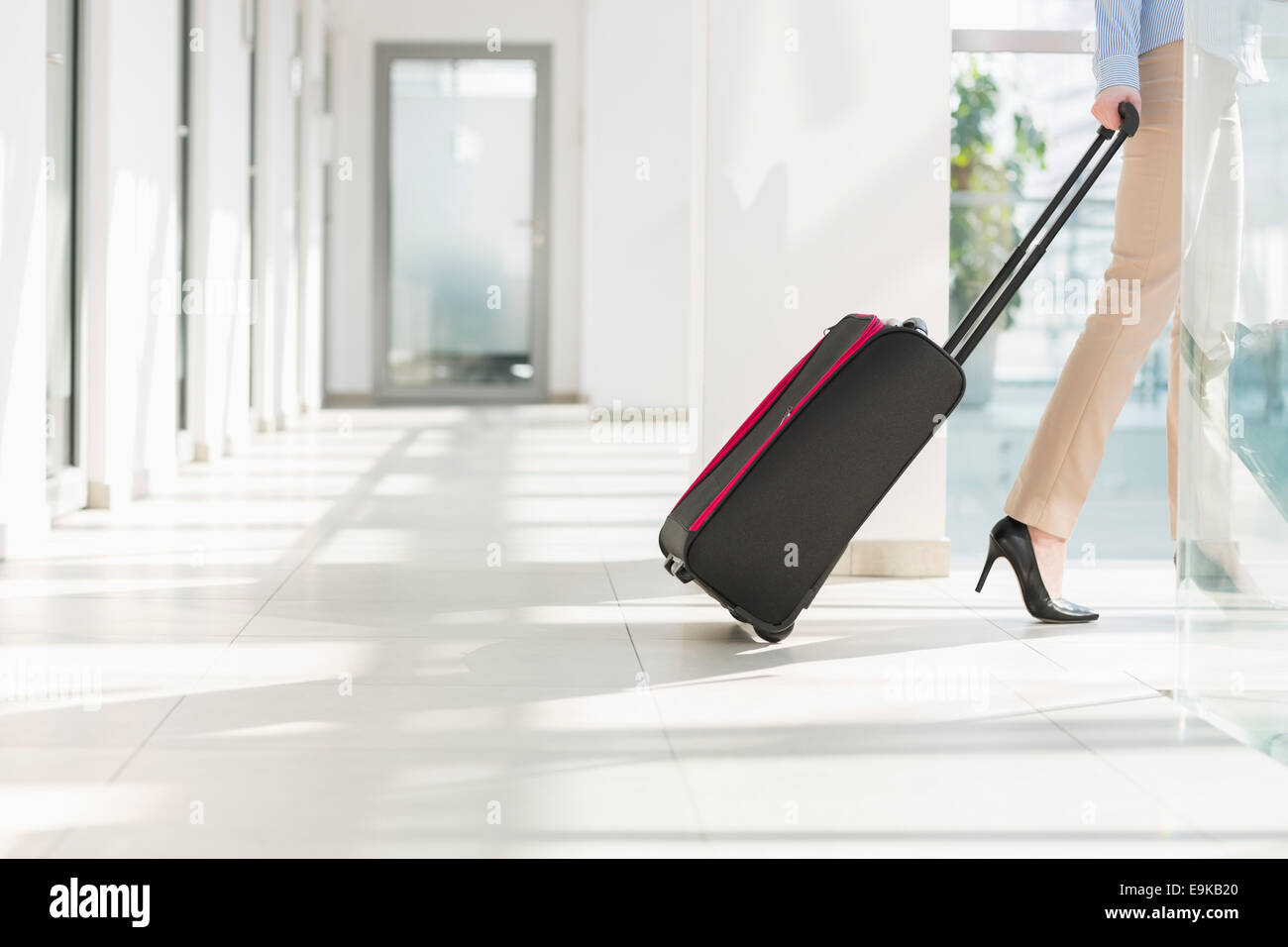 Low section of businesswoman with luggage leaving airport Stock Photo