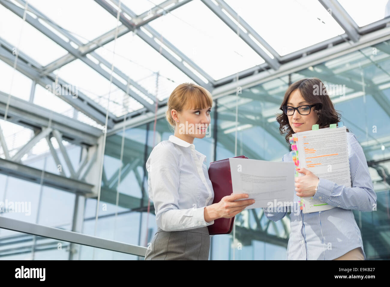 Mid-adult businesswoman showing document to female colleague in office Stock Photo