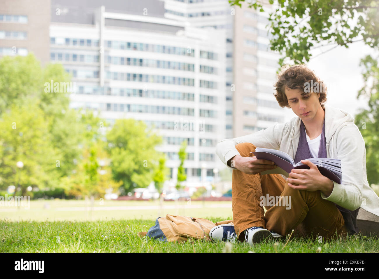 Full length of young man reading book on college campus Stock Photo
