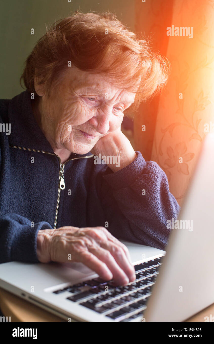 Old woman checks the mail on a laptop. Stock Photo