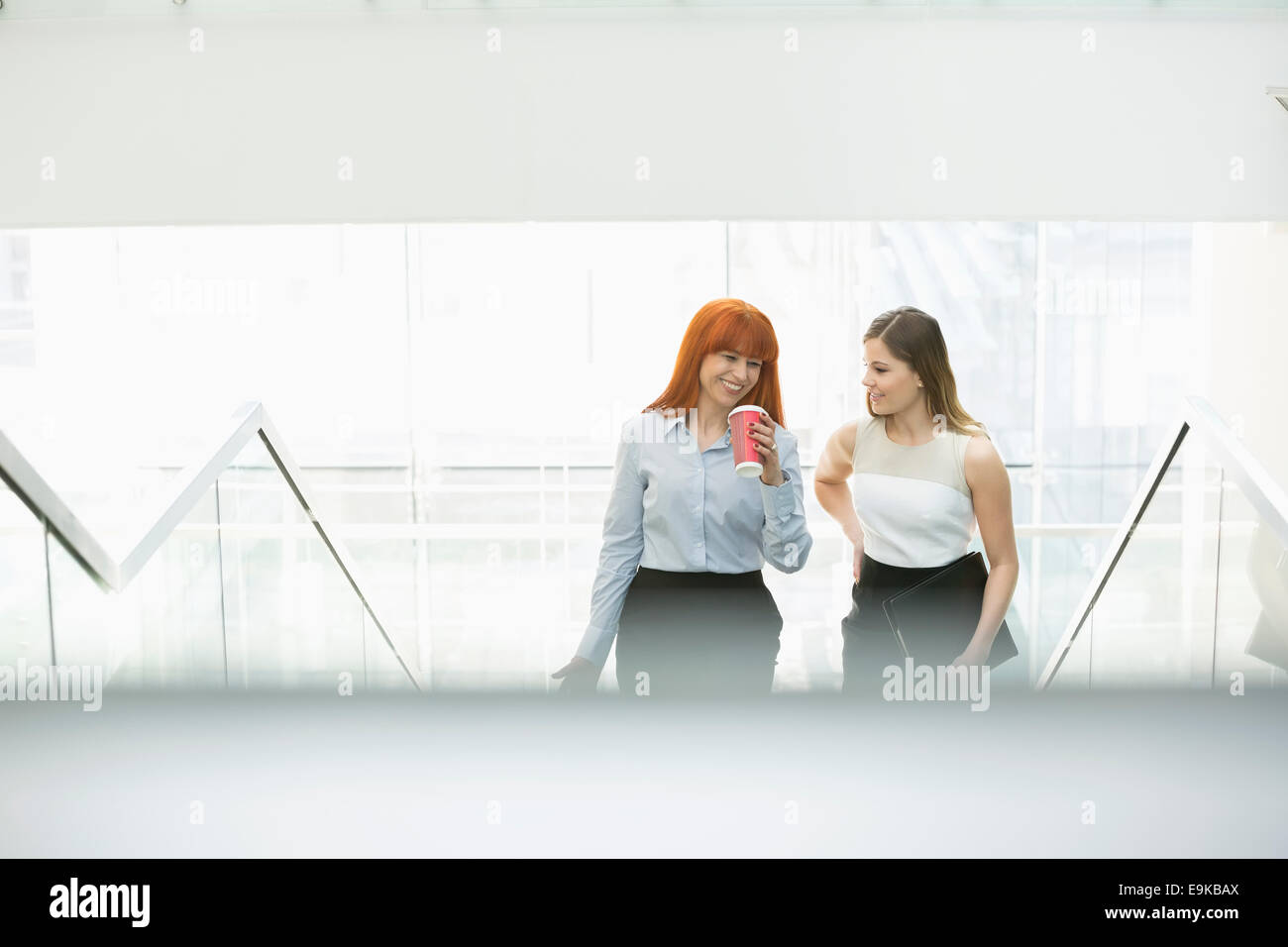 Businesswomen having coffee while moving up steps in office Stock Photo