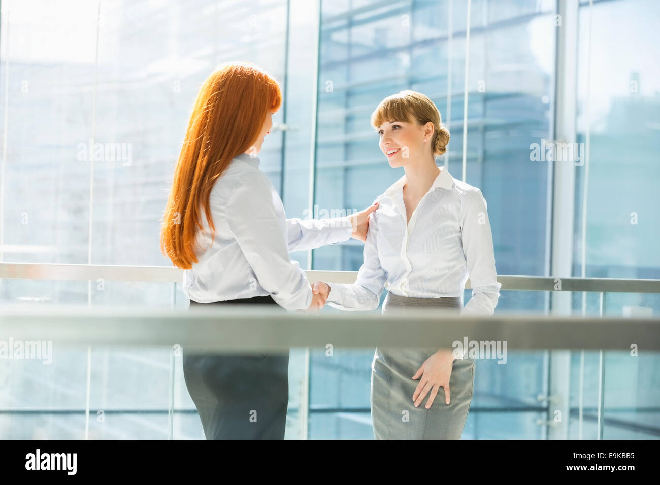Businesswomen shaking hands in office Stock Photo