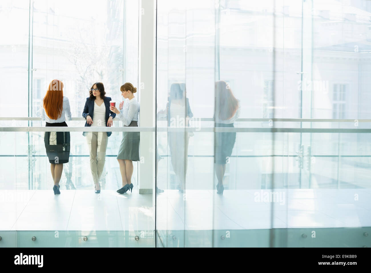 Businesswomen conversing at office hallway Stock Photo