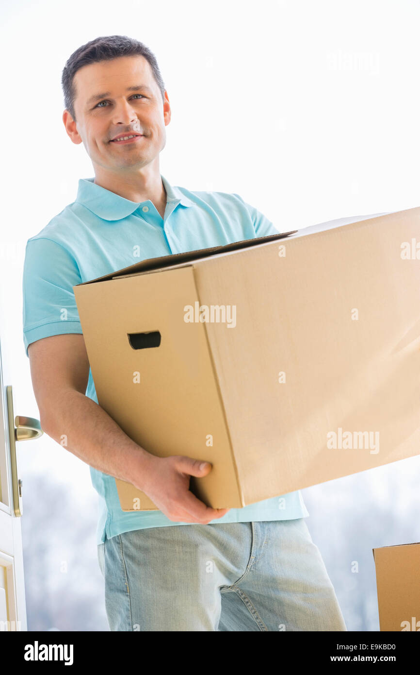 Man looking away while carrying cardboard box while entering new house Stock Photo