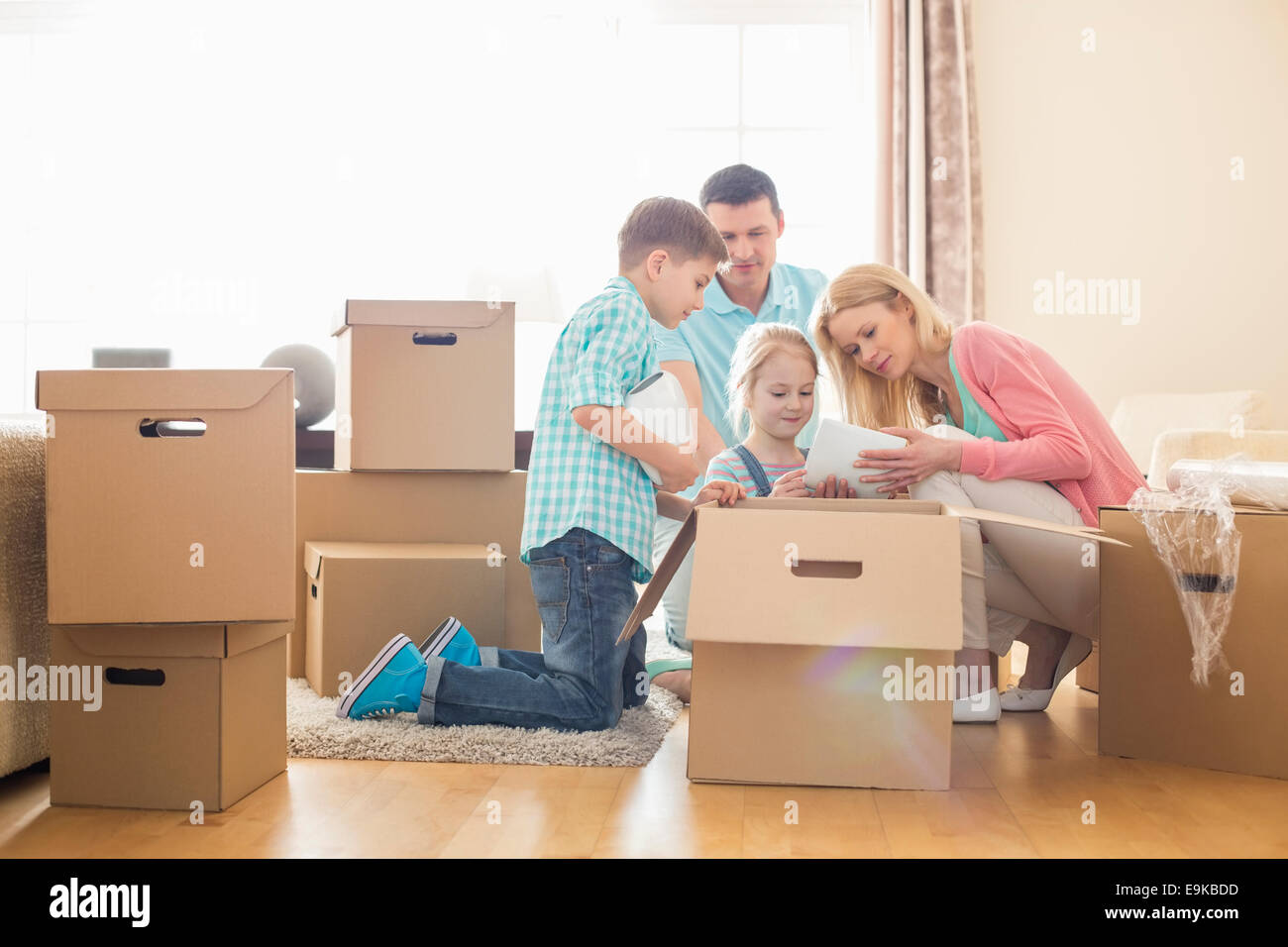 Family unpacking cardboard boxes at new home Stock Photo