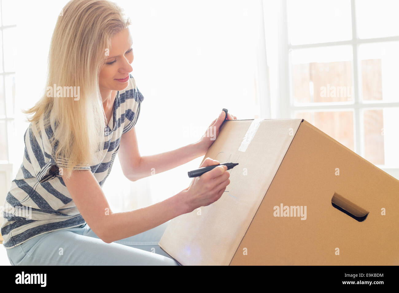 Woman labeling moving box at home Stock Photo