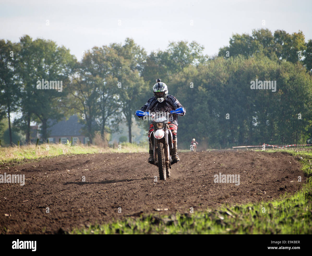 Enduro motorcyclist with Gopro camera on his helmet riding through a farm field in Ruurlo, the Netherlands. Stock Photo