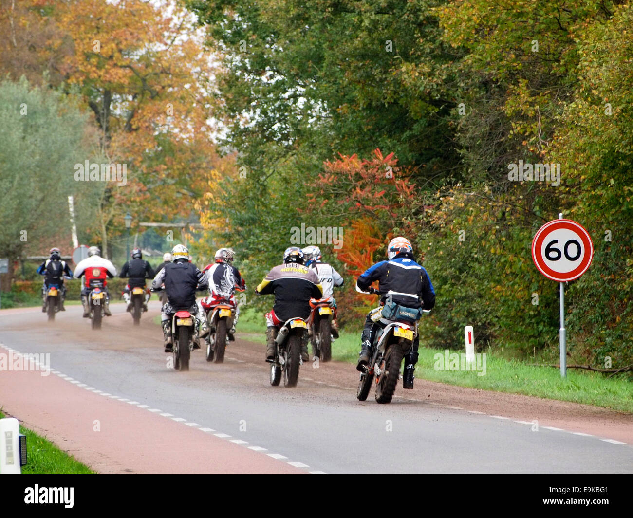 group of men on offroad enduro motorcycles passing 60 kmh speed limit sign in Ruurlo, the Netherlands Stock Photo