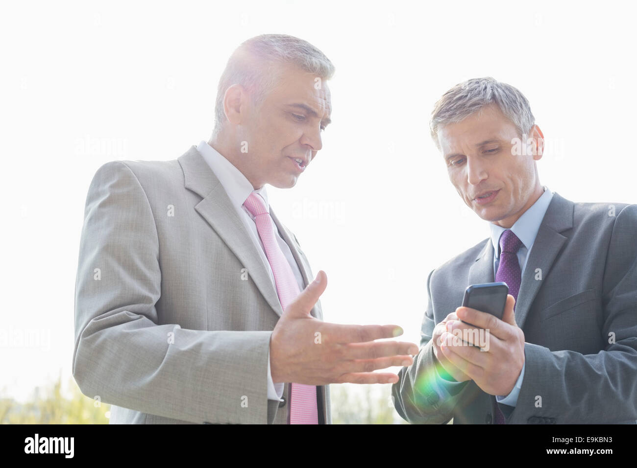 Businessmen discussing over mobile phone outdoors Stock Photo