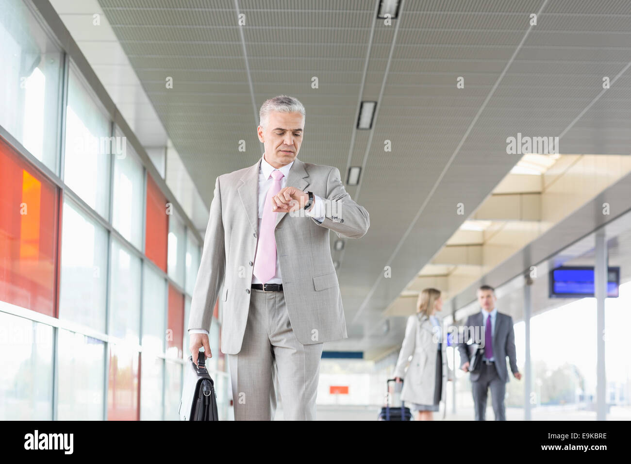 Middle aged businessman checking time with colleagues in background at ...