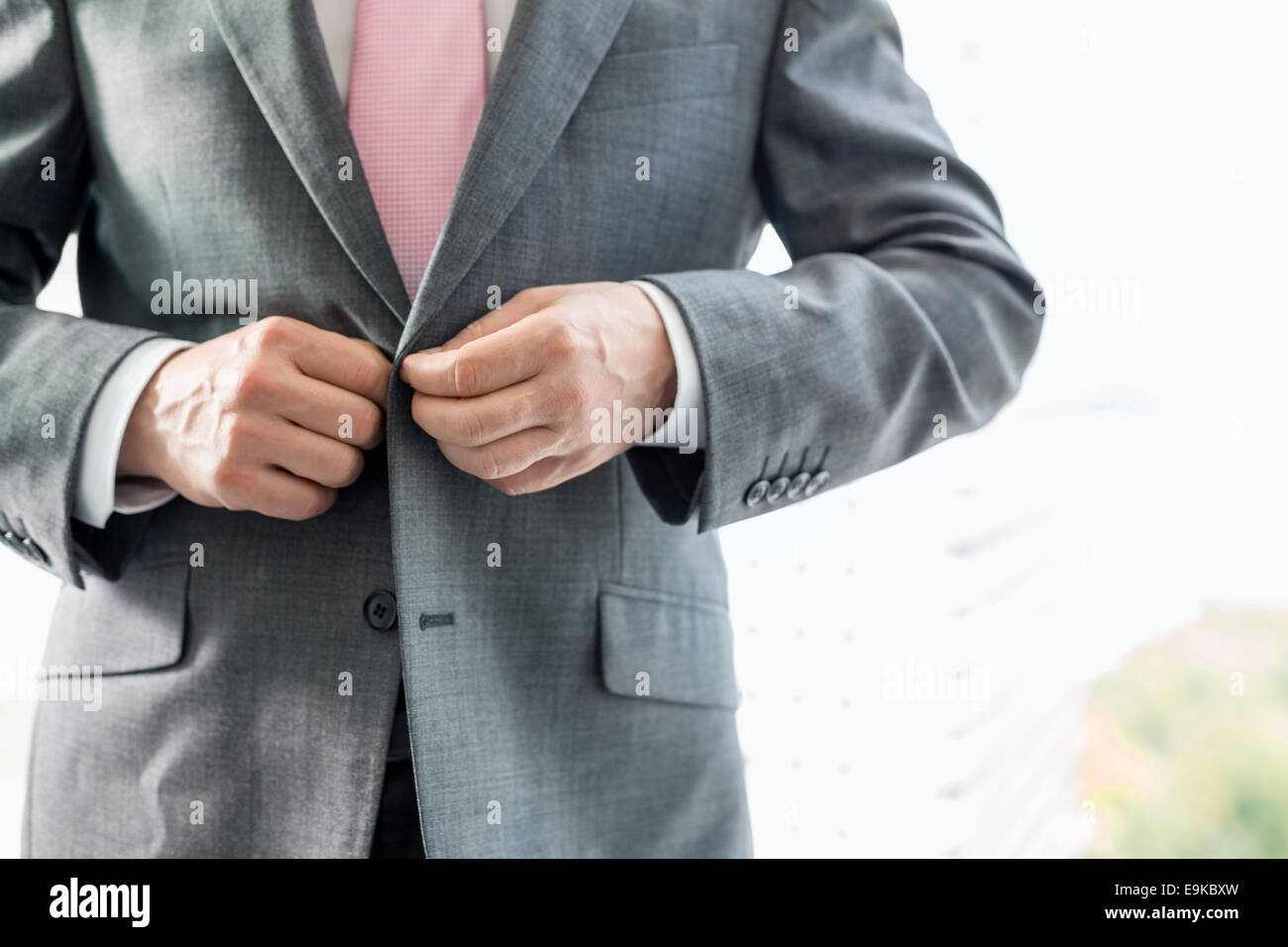 Midsection of mature businessman buttoning his blazer Stock Photo