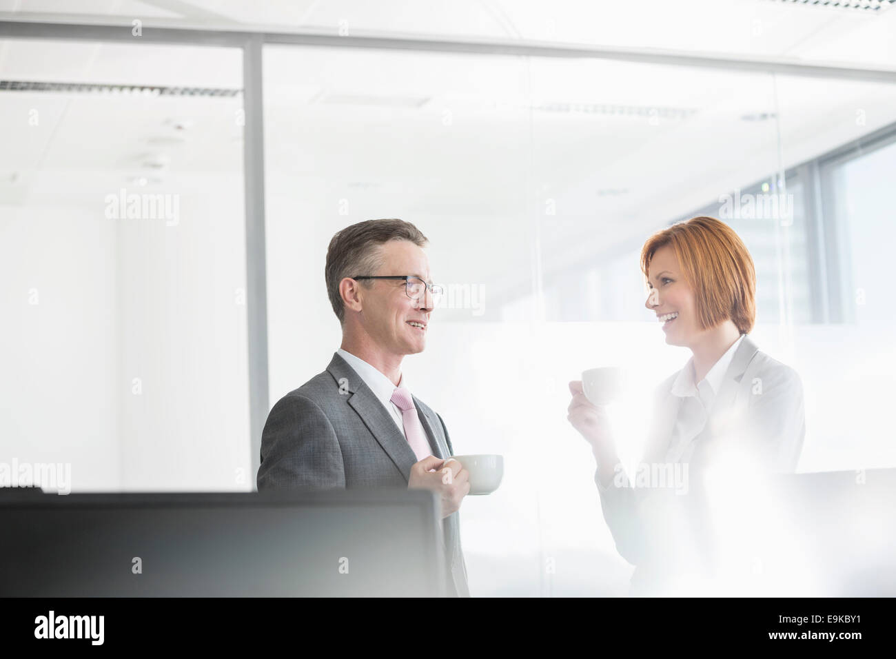 Businessman and businesswoman having coffee in office Stock Photo - Alamy