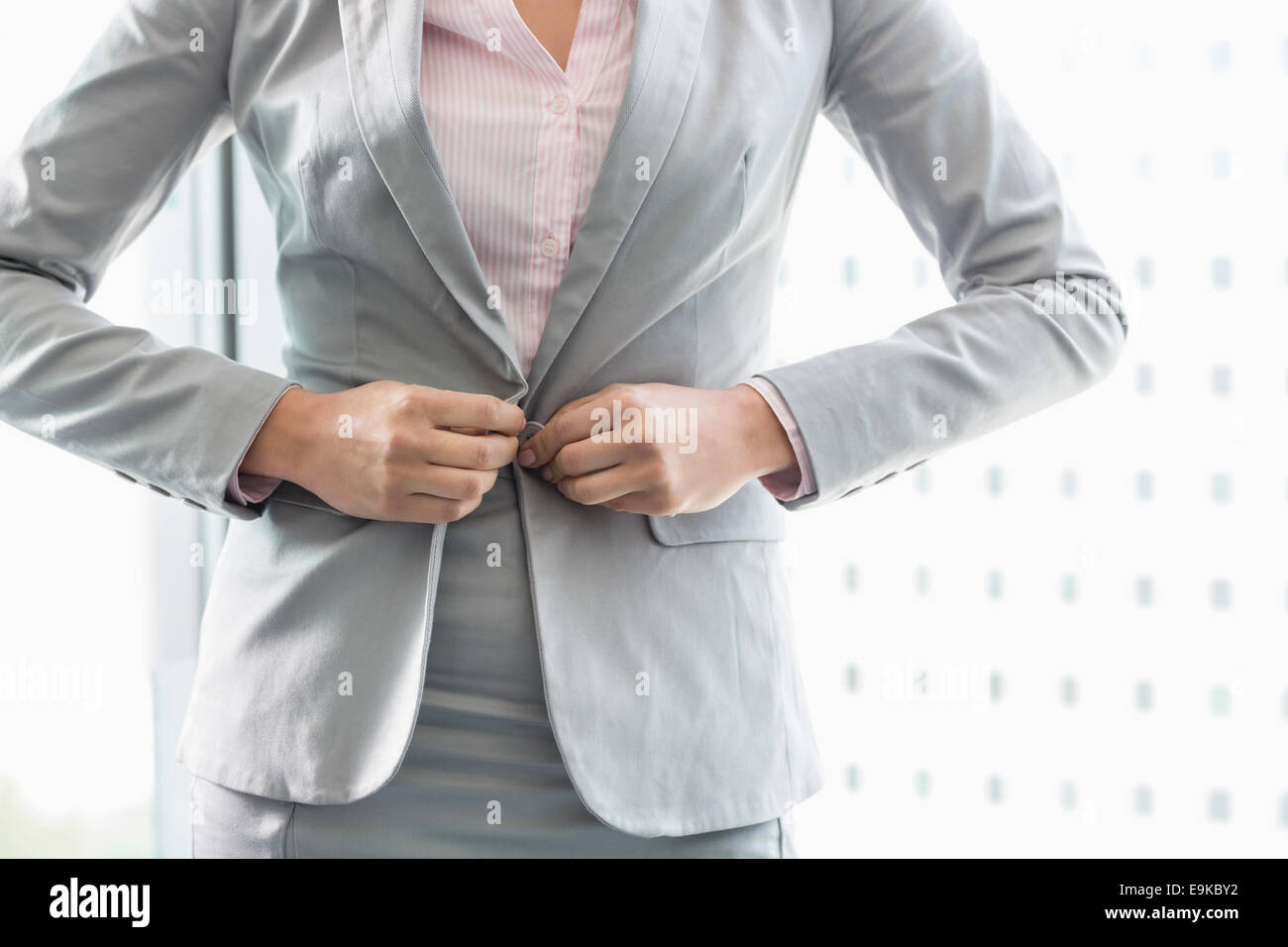 Midsection of businesswoman buttoning her blazer Stock Photo
