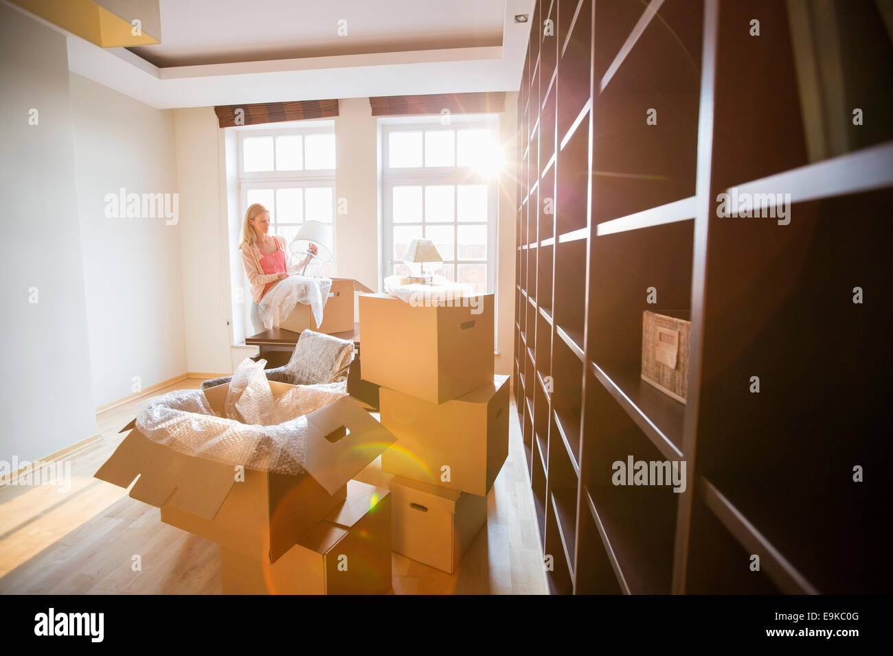 Woman unpacking lamp from moving box at new house Stock Photo