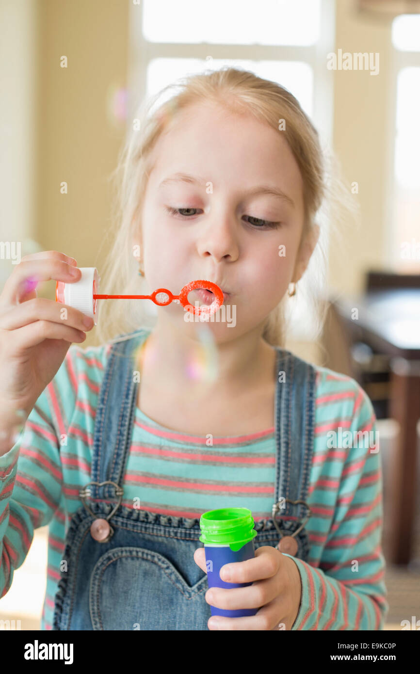 Cute girl playing with bubble wand at home Stock Photo