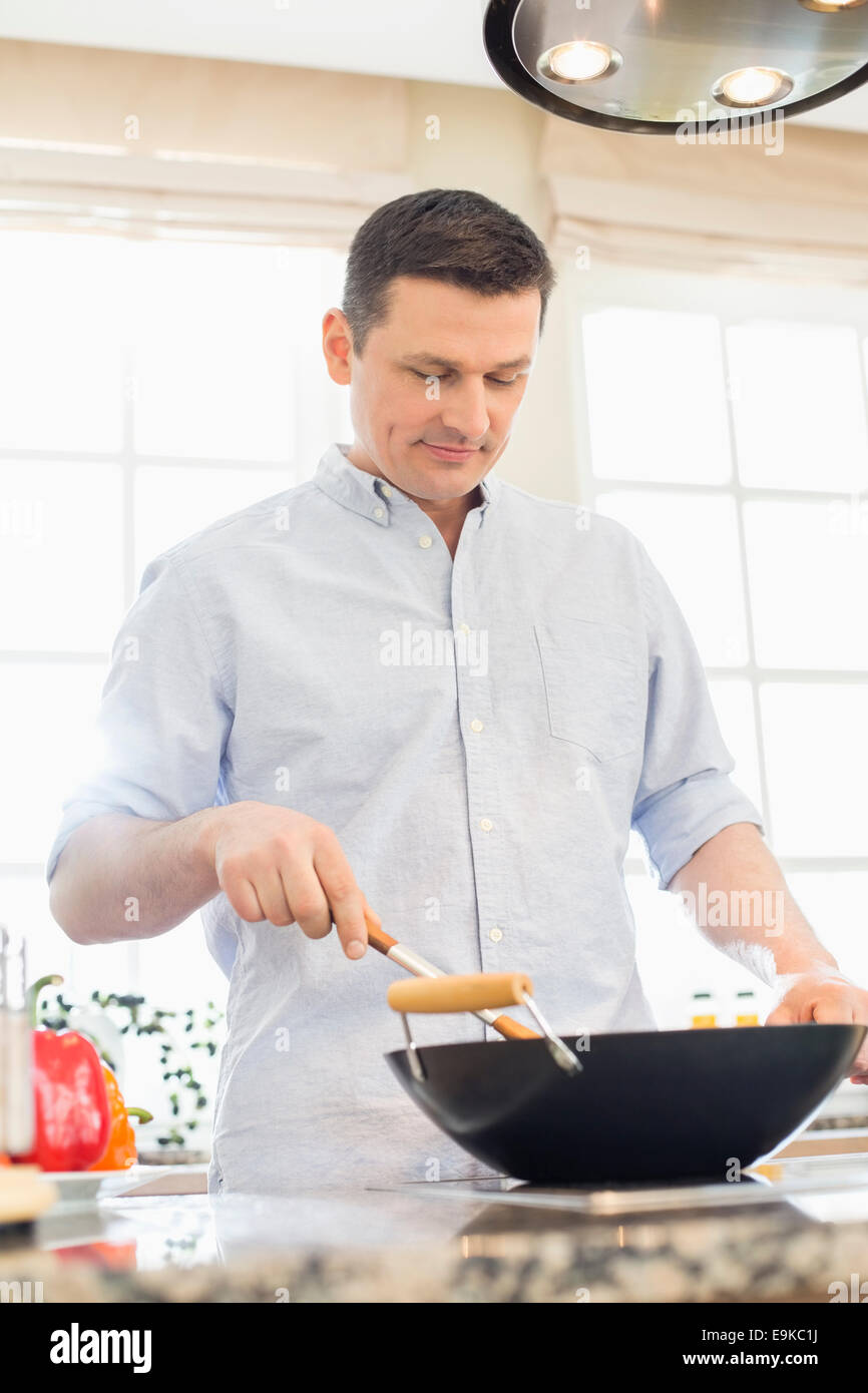 Middle-aged man cooking in kitchen Stock Photo