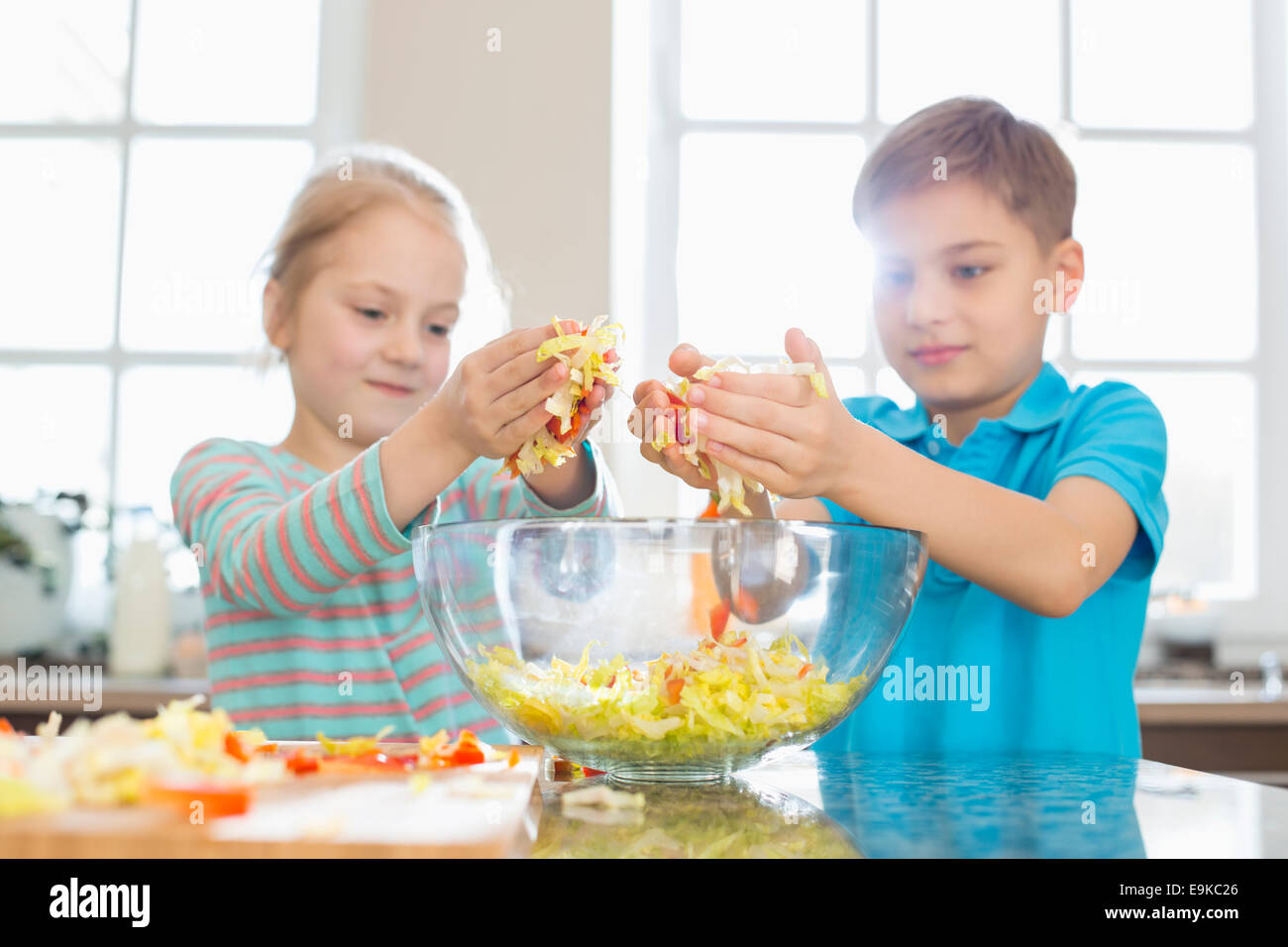 Brother and sister preparing salad in kitchen Stock Photo