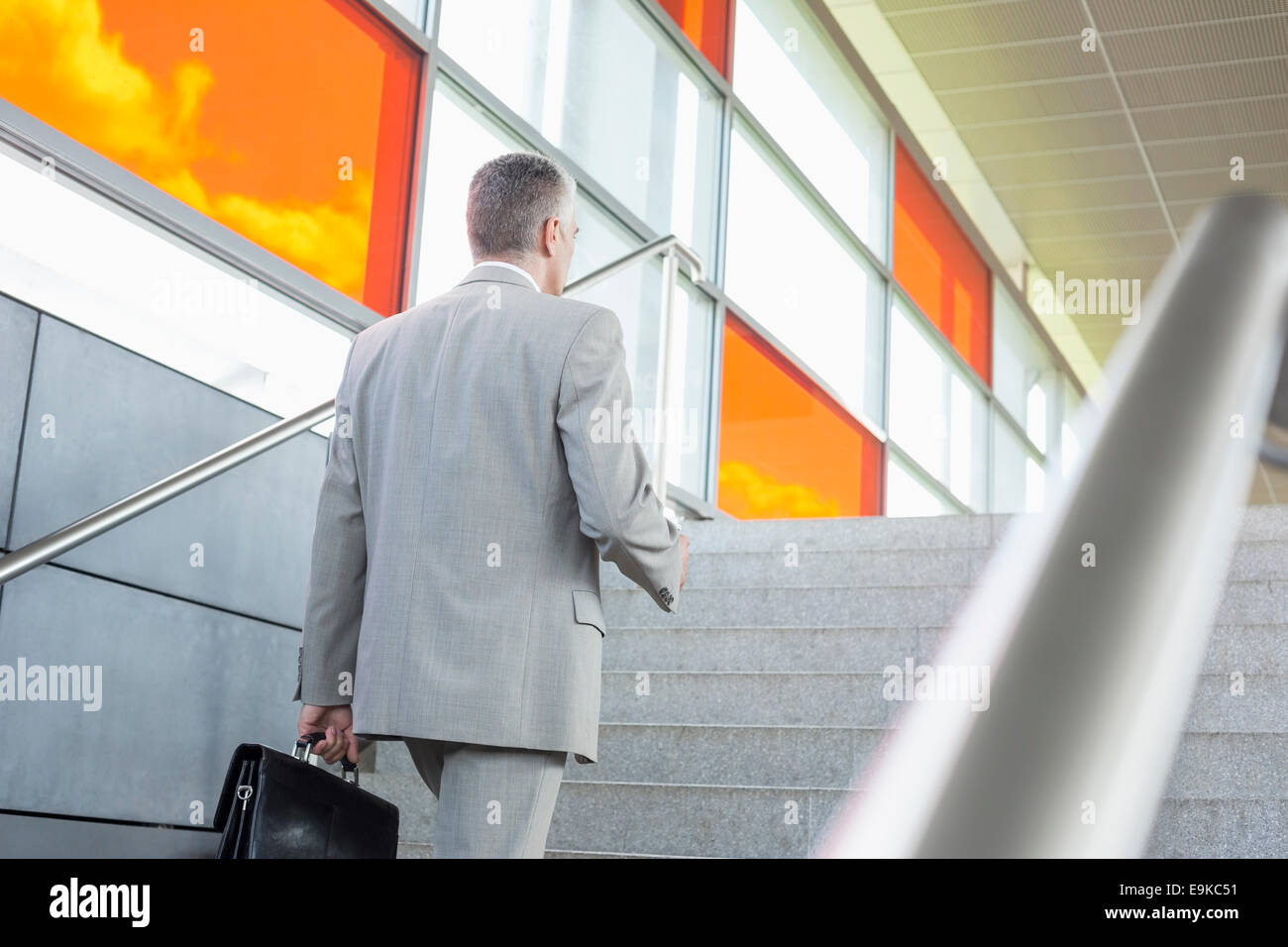 Rear view of middle aged businessman walking up stairs in railroad station Stock Photo
