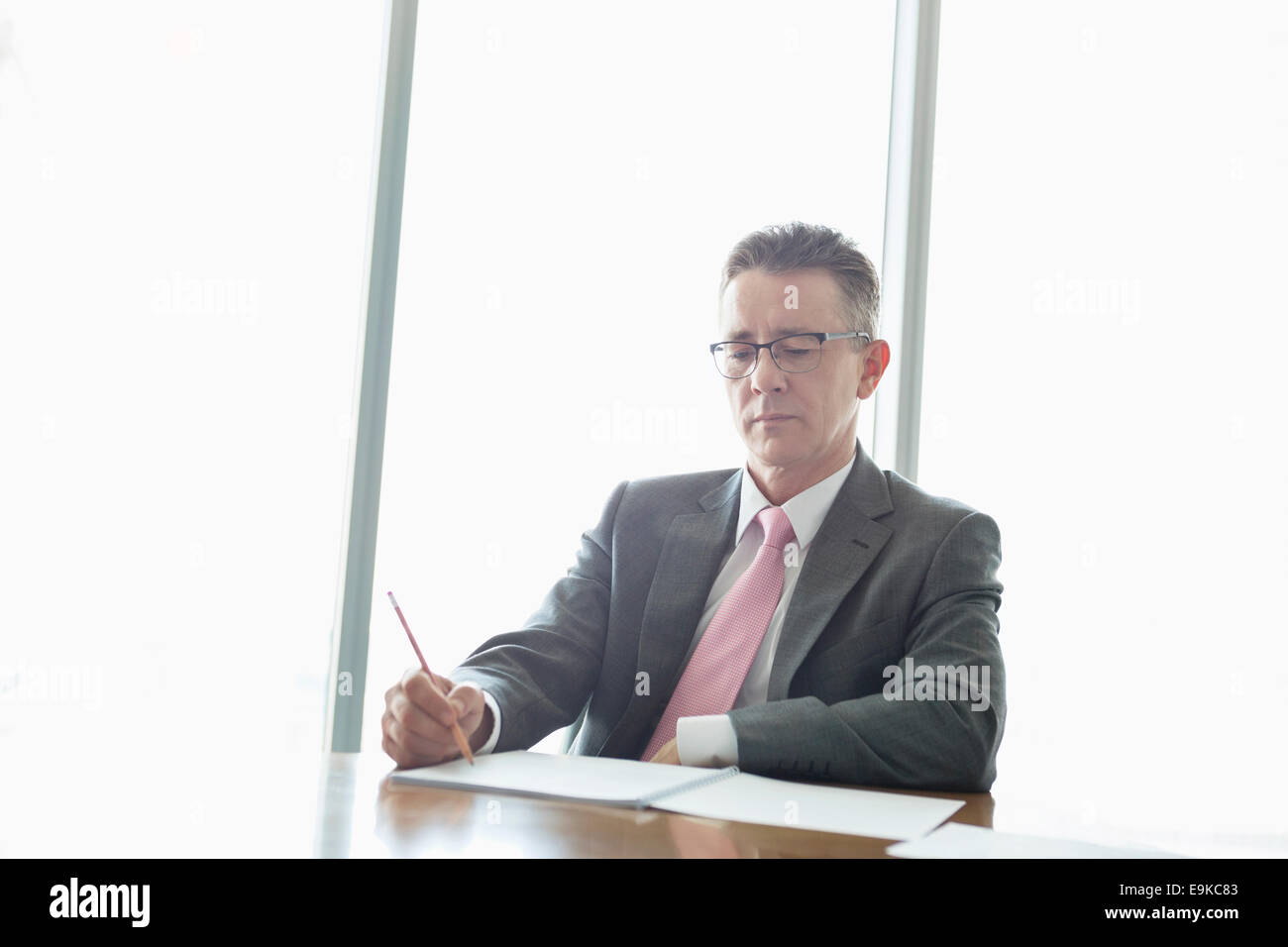 Mature businessman writing on book at table in office Stock Photo